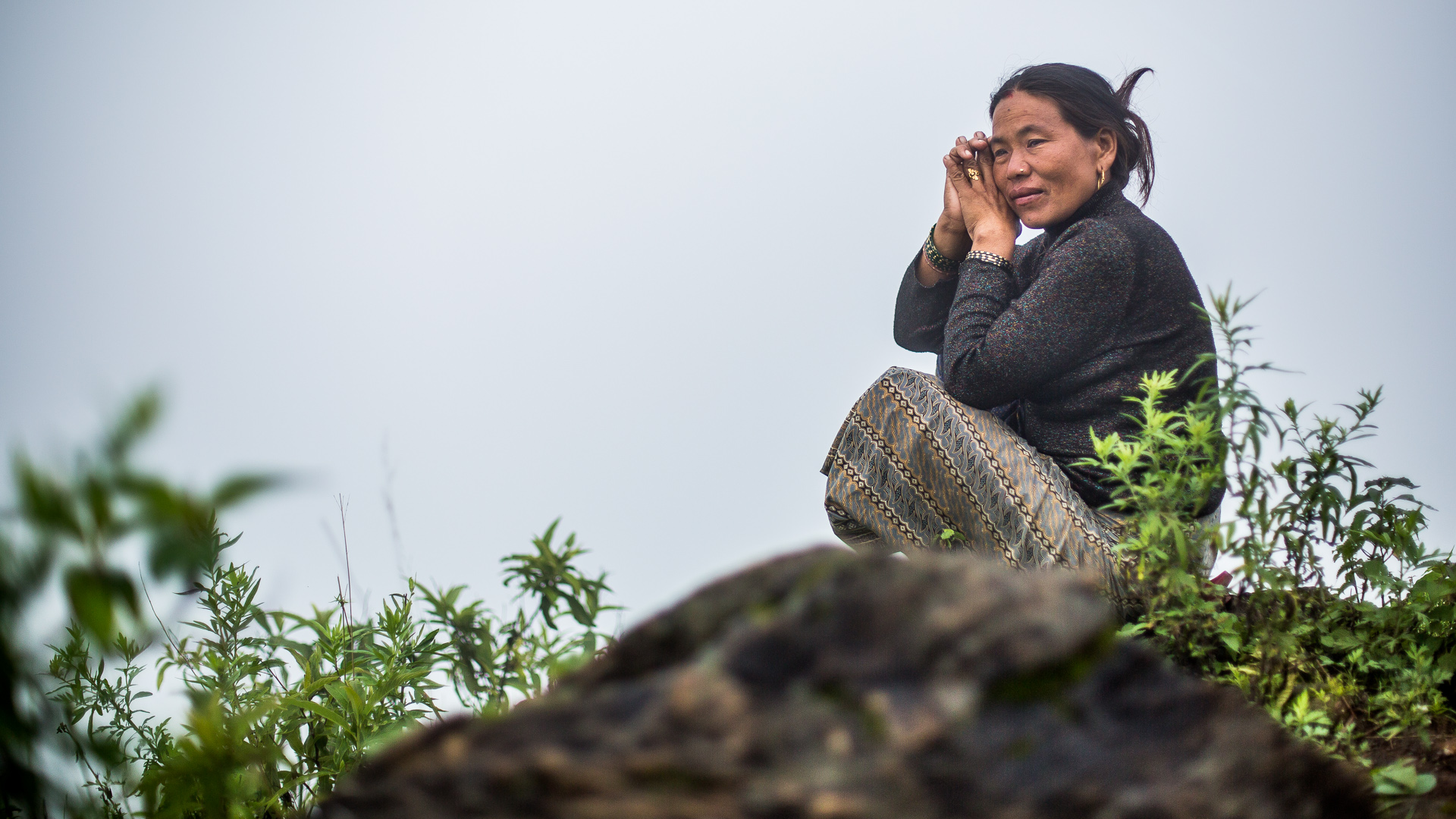Lady who lost her house and family looking over the valley thinking about past and future.