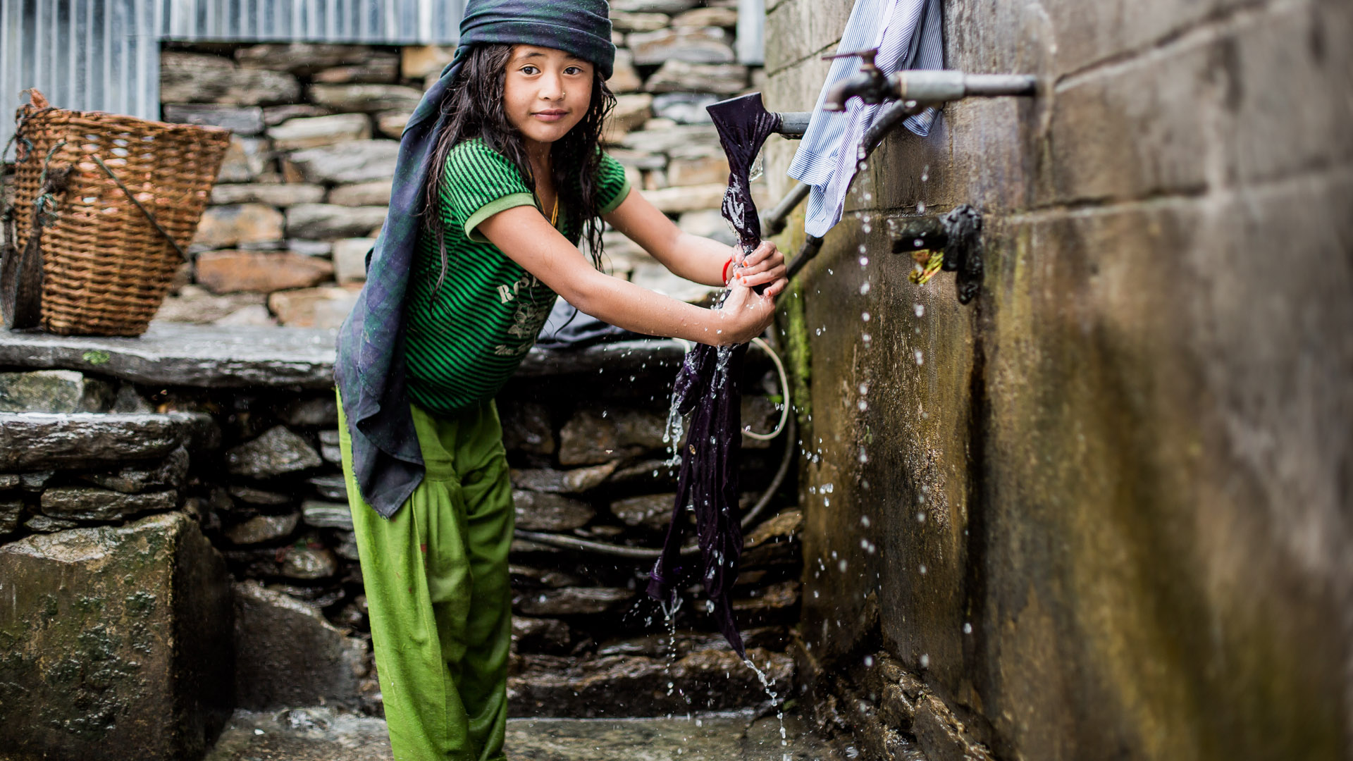 Young girl washing her clothes at a local water tap. Girls are usually helping from very young age in all housekeeping, cleaning and cooking. 