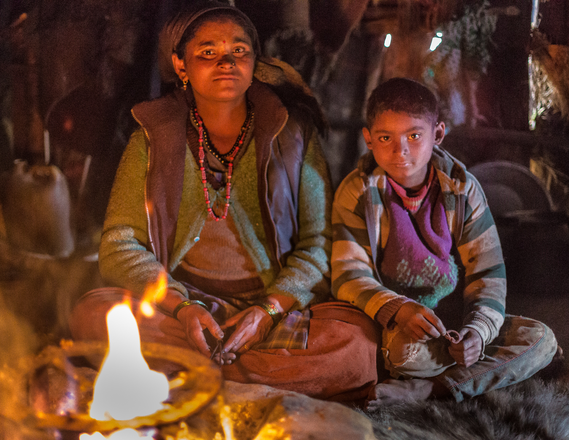 Sumit and his mother siting by the fire. This is the place where they prepare food, eat and sleep.