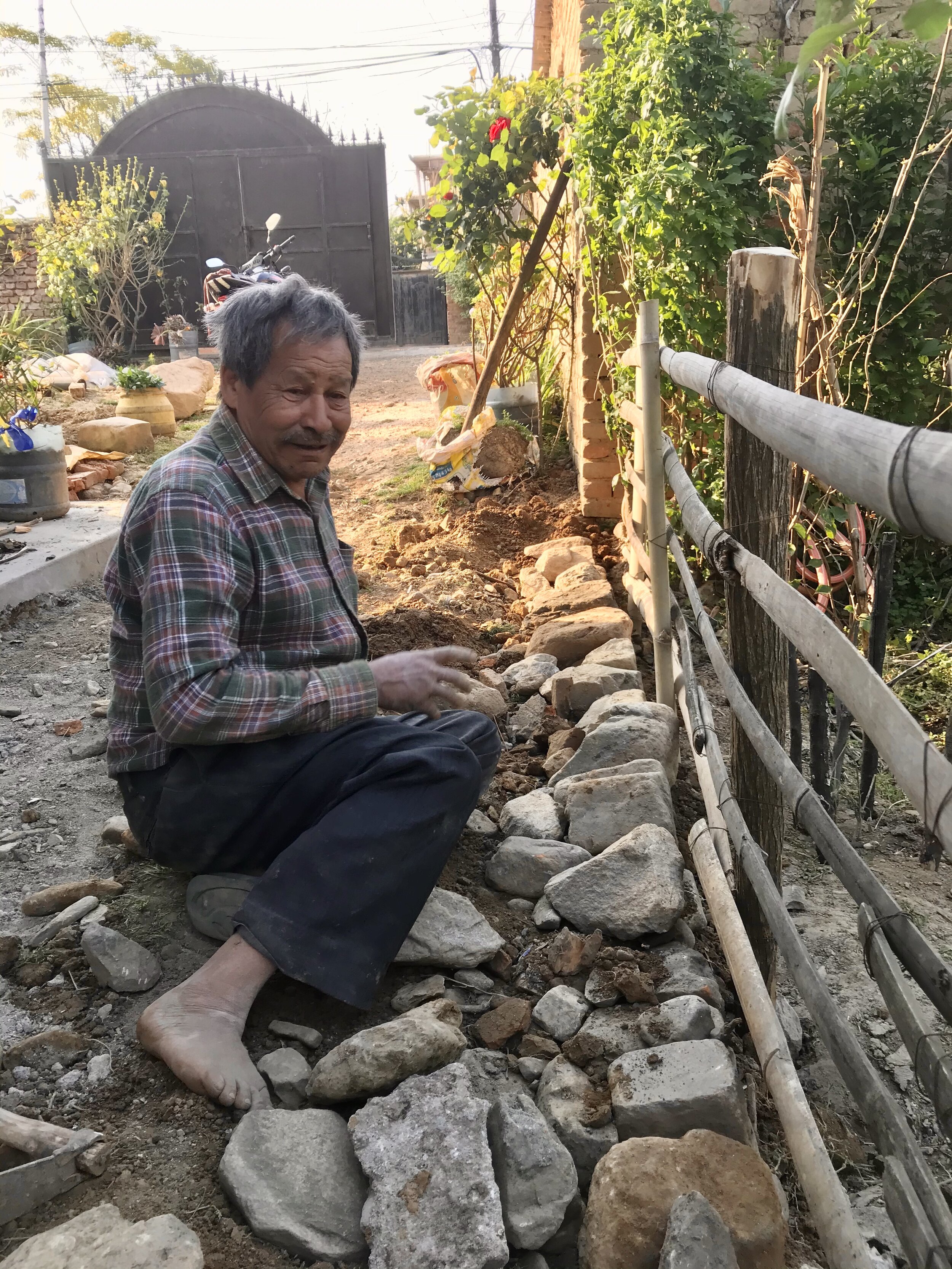  Nadat het nieuwe hekwerk van bamboe af is werkt vader werkt aan de versteviging en ophogen van het pad. 