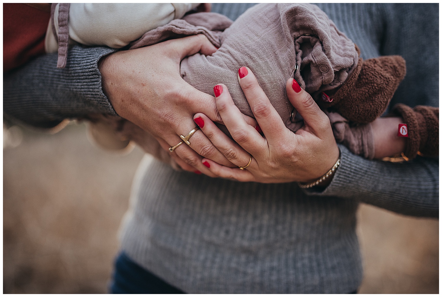 mother holding baby in field at sunset