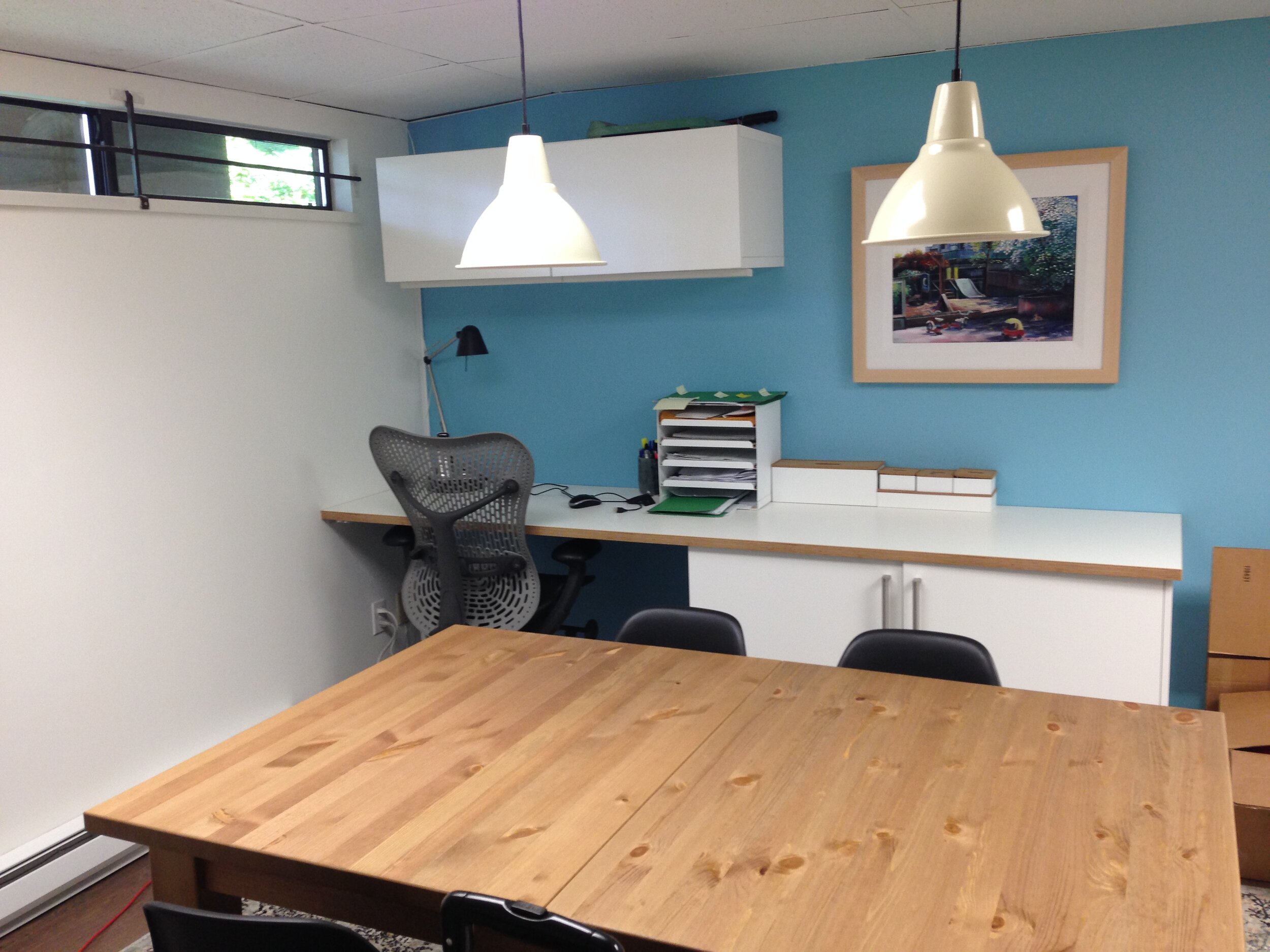 Work are with wall storage and flexible table with pendant lights.