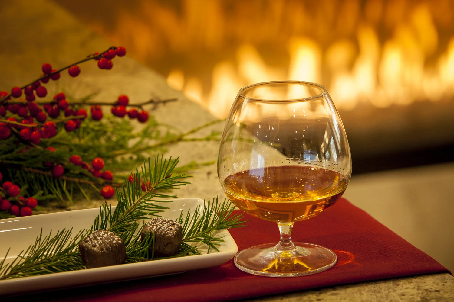 Styling for photoshoot of brandy glass and berries with fireplace in background.