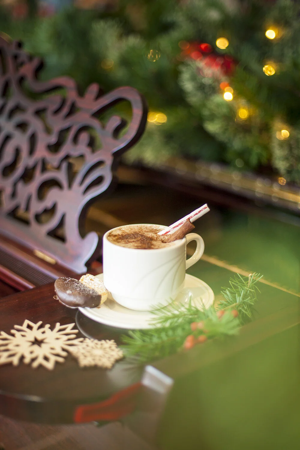 Photo styling of cup of hot chocolate, cinnamon stick, peppermint stick and seasonal wood snowflake accessories.