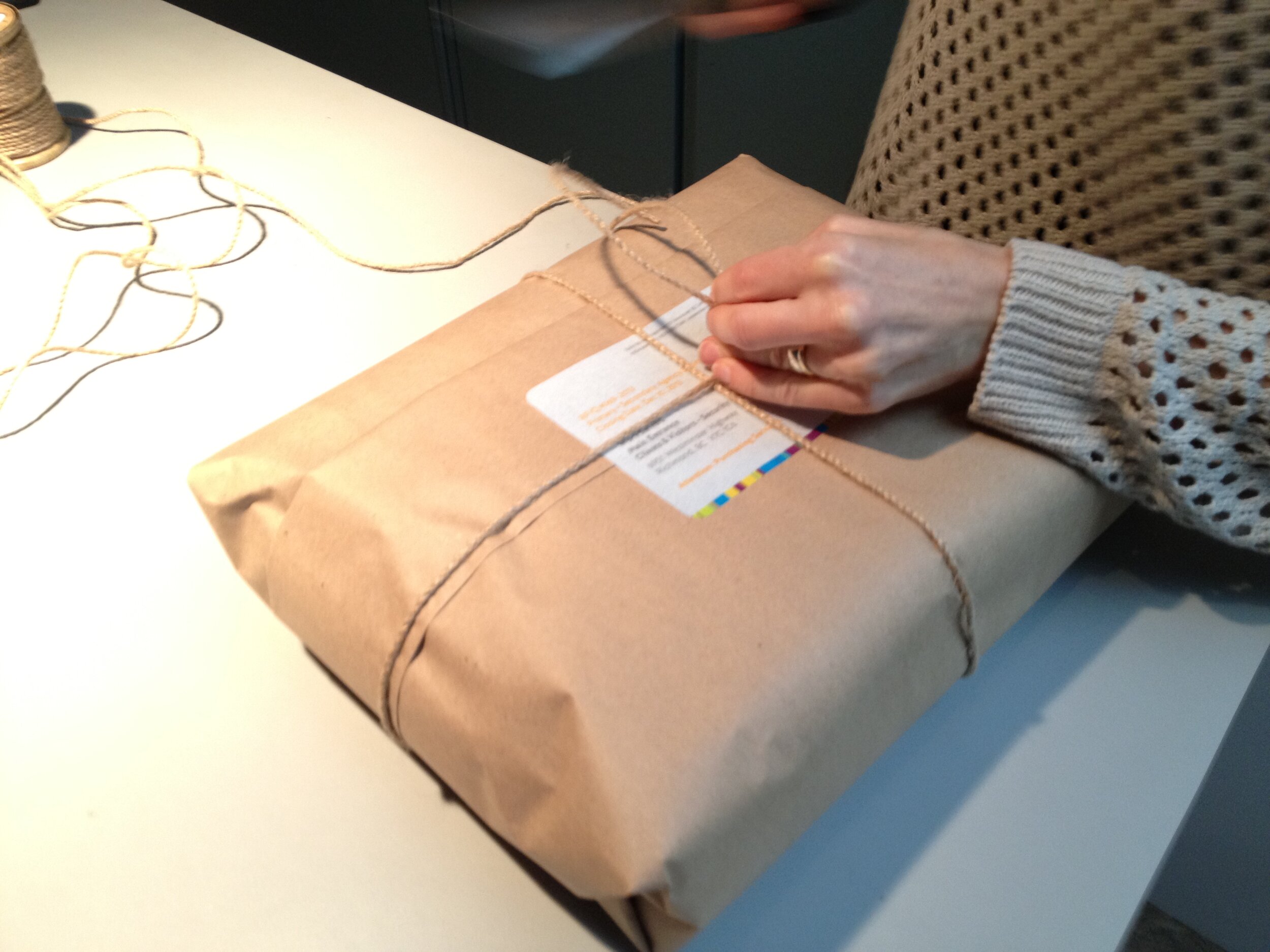 Packaging up laptop bags in brown paper and natural twine for shipping.