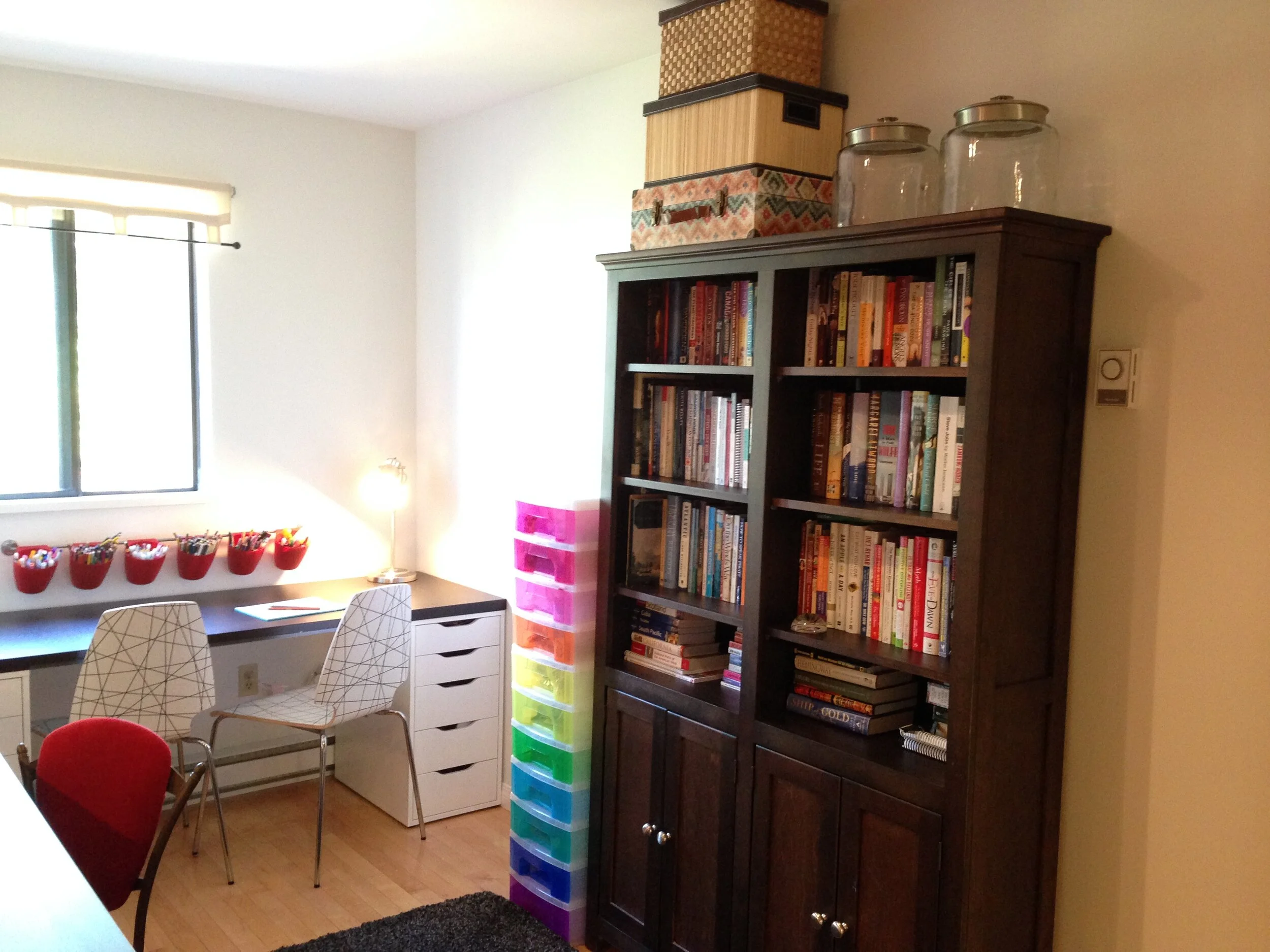 Kids craft work area with modern white chairs and bookshelf.