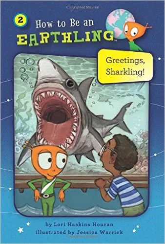 Children and a fish with glasses looking at a large shark in an aquarium. The cover has bright colors and an illustration of a shark with its mouth open, and a small fish with a speech bubble saying 'Greetings, Sharkling!'