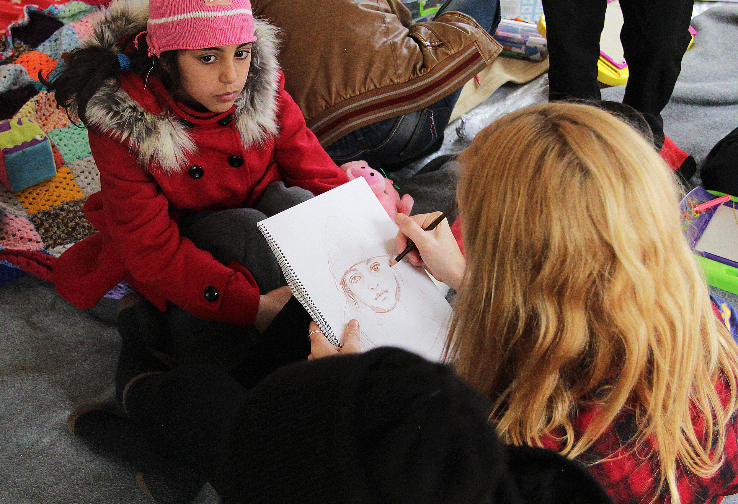 Aubrey Roemer drawing portraits at Children's Protection Play Center at Refugee Camp Moria, 2015. Photo courtesy of Bob Miller.
