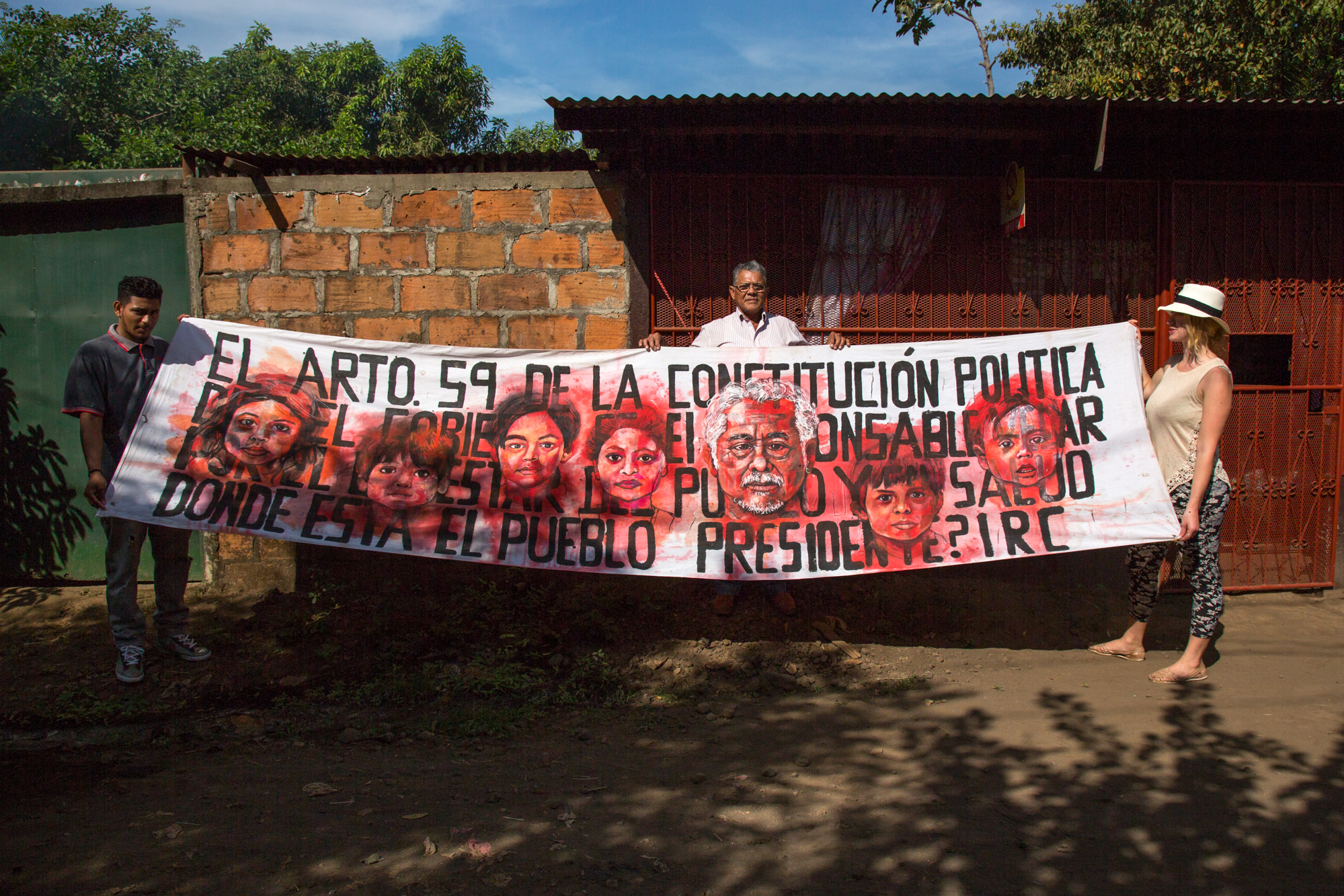 Artist Aubrey Roemer, assistant Bryan Maldonado, and La Isla Foundation cofounder, Juan Salgado, looking at a painted protest banner in Chichigalp, Nicaragua, 2015. Photo courtesy of Tom Laffay. 
