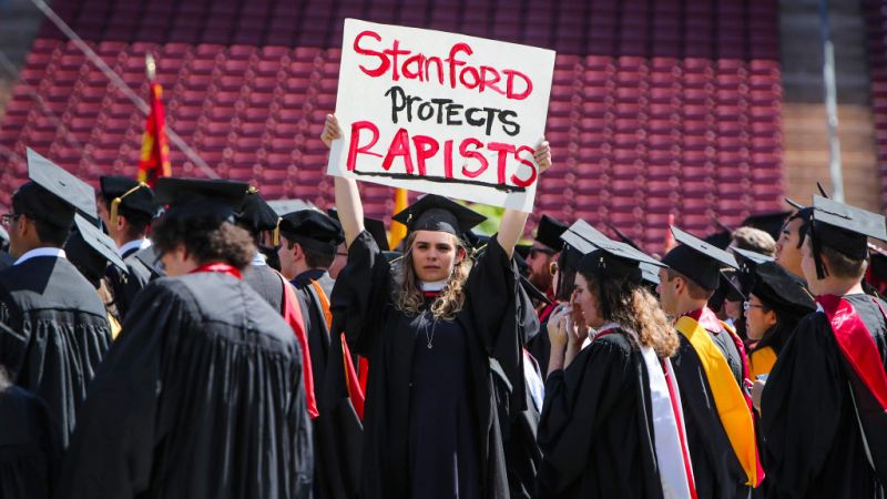 Andrea Lorei holds up a sign during the 125th Commencement ceremony at Stanford. (Image: Yahoo News ) Many students held aloft signs of protests to call attention to the University's handling of rape cases. ( Los Angeles Times )