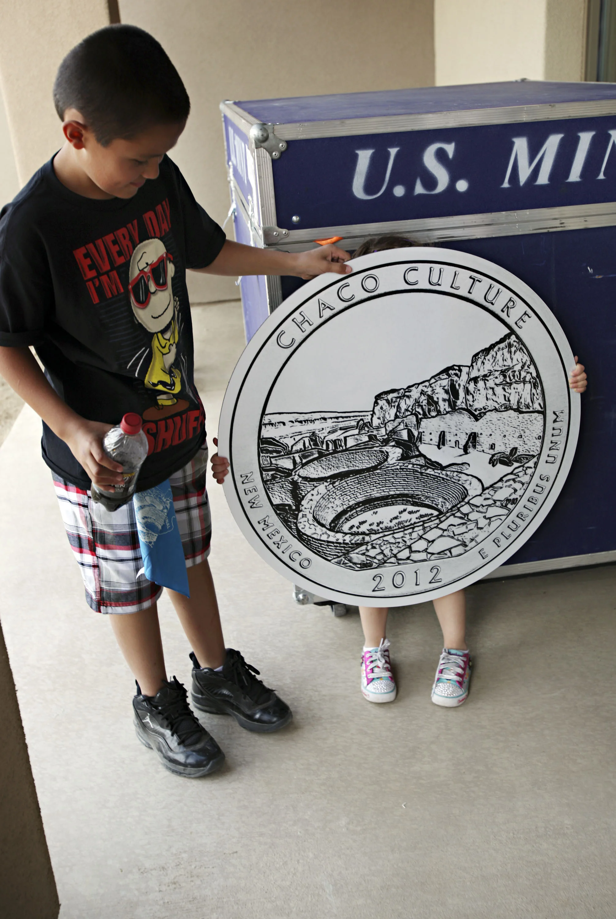 Peyton Gallegos, 3, hides behind the Chaco Canyon quarter prop after posing for a photo with her brother, Timothy Gallegos, 11, after the official quarter launch at Chaco Canyon, Thursday, April 26, 2012. The children were visiting with their mother, Denise Gallegos from Chama. (Morgan Petroski/Albuquerque Journal)