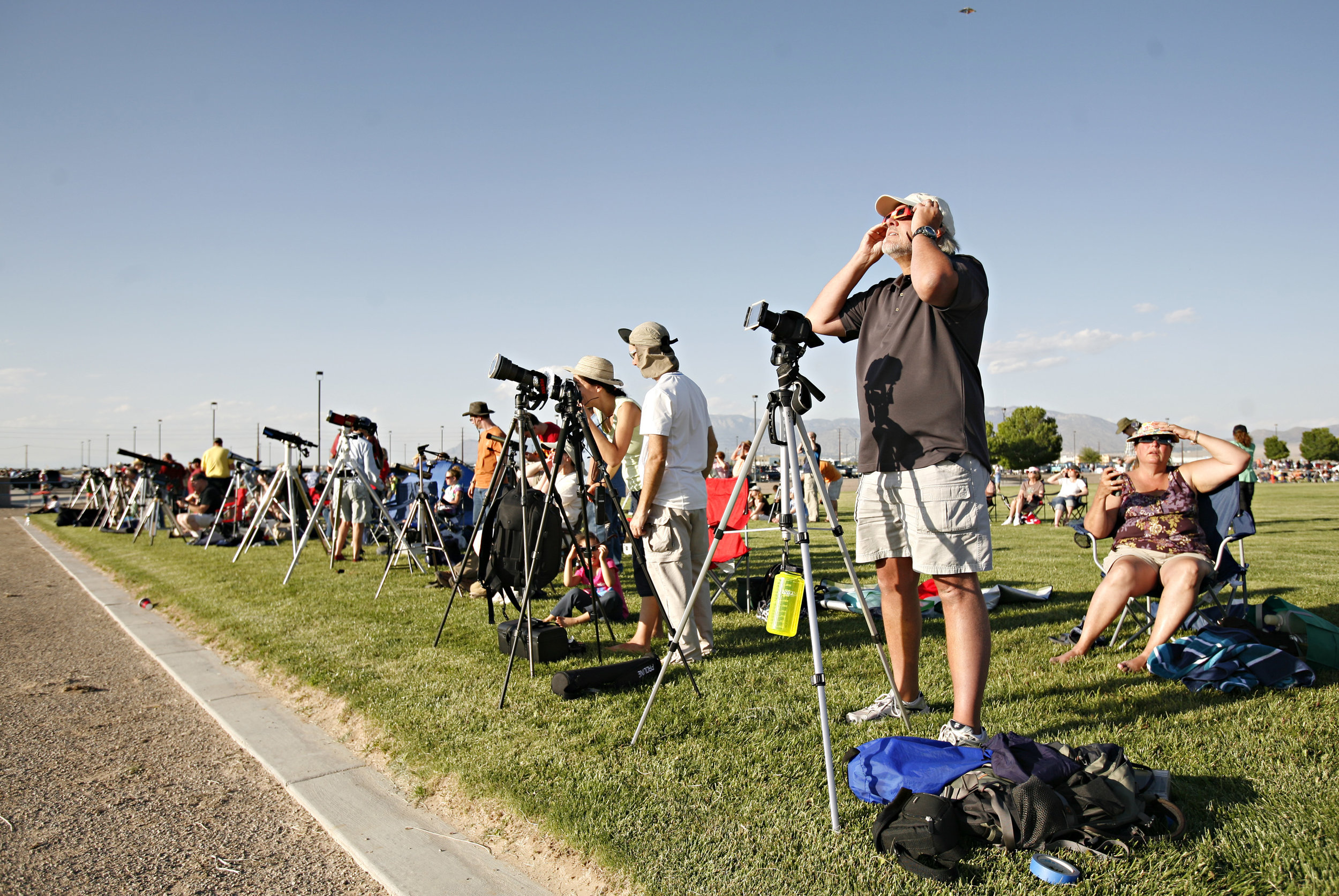  Second from the right, Cal Harr, from Centennial, CO, takes a look through his solar glasses while getting his camera set up to photograph the annular solar eclipse while taking part in the viewing party near the Hard Rock Casino Presents the Pavili