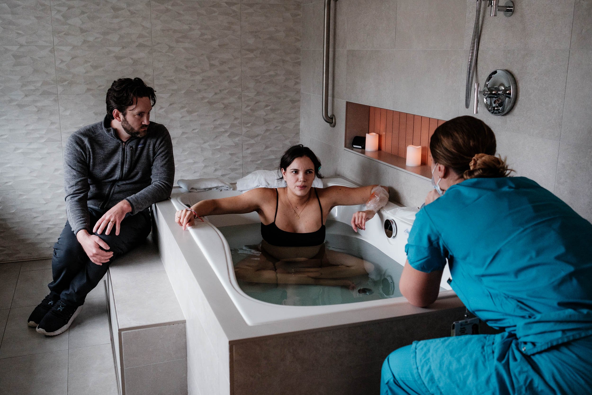 A mother labors in the birth tub while surrounded by her husband and midwife at Virginia Mason in Seattle.