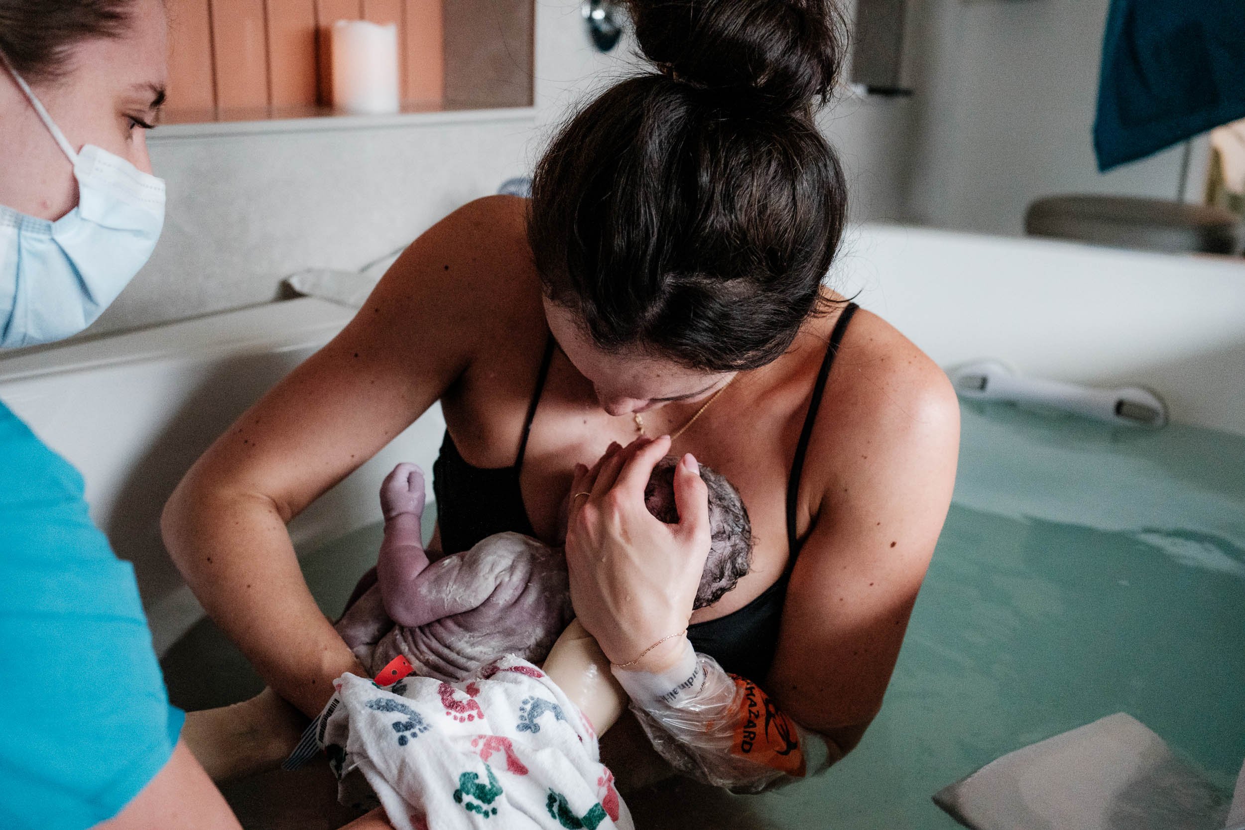 A mother brings her baby up to her chest immediately after giving birth to him in a birth tub at Virginia Mason in Seattle.