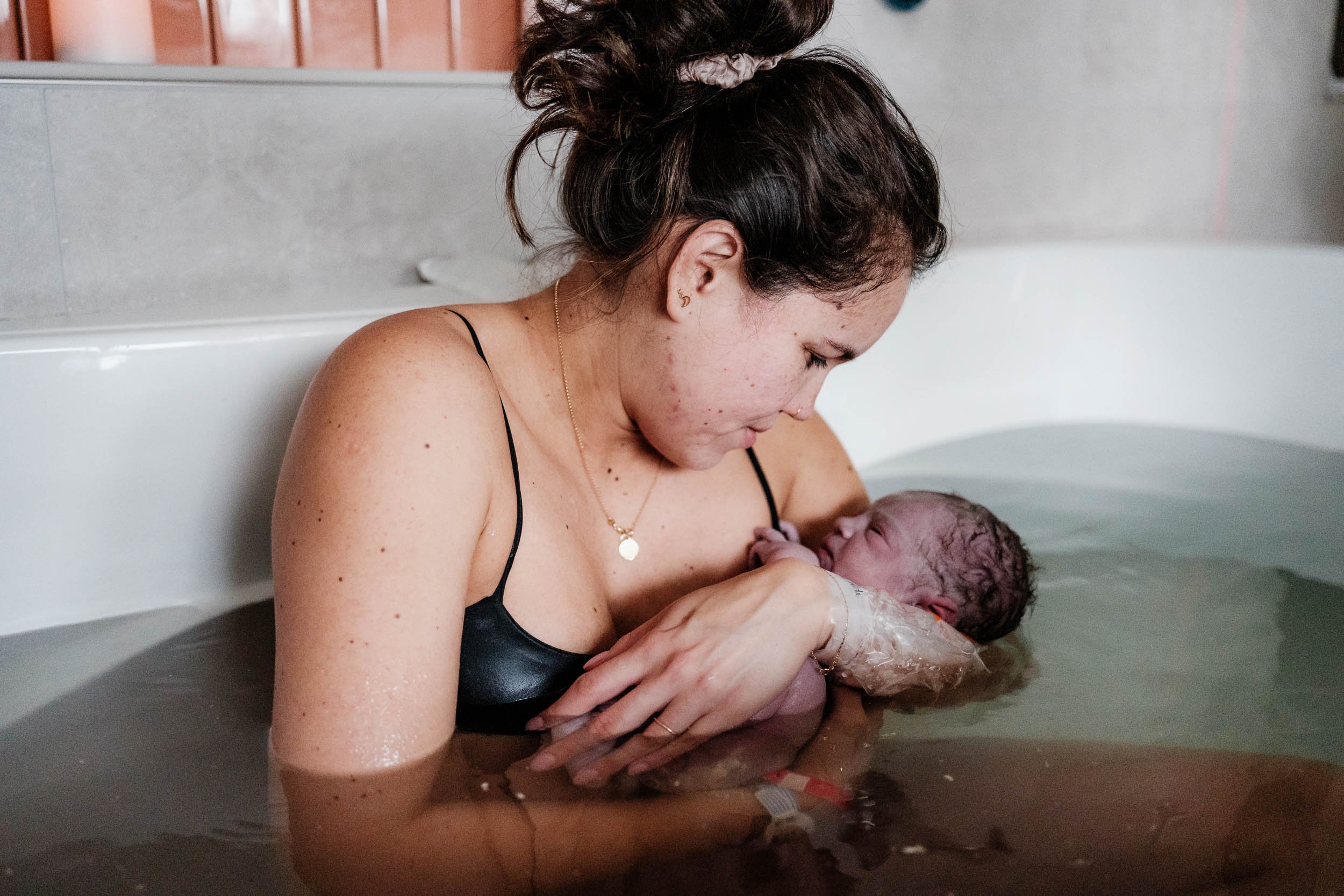 A mother looks adoringly at her freshly born baby in the birth tub at Virginia Mason in Seattle.