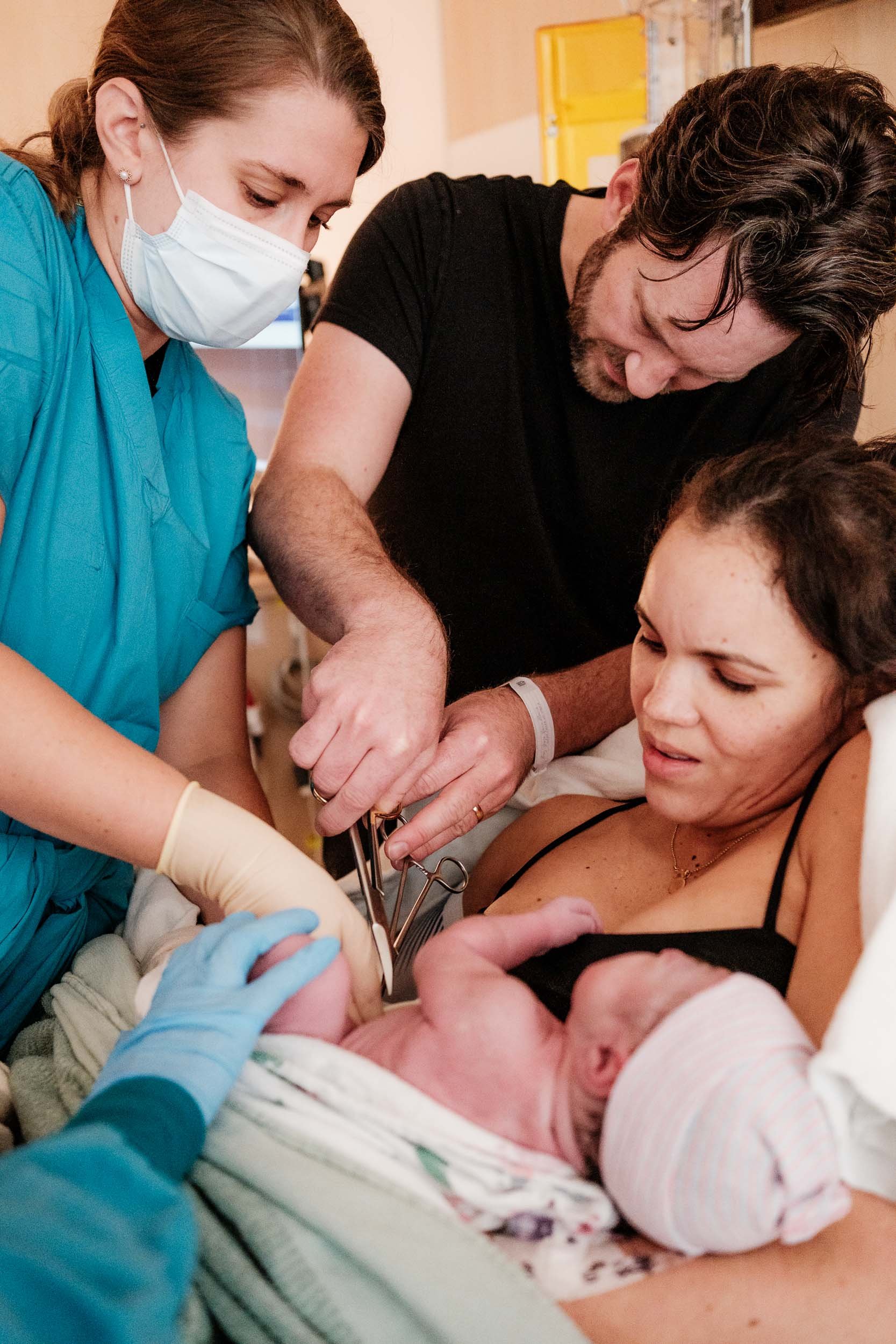 A father cuts the cord of his newborn baby at the hospital.