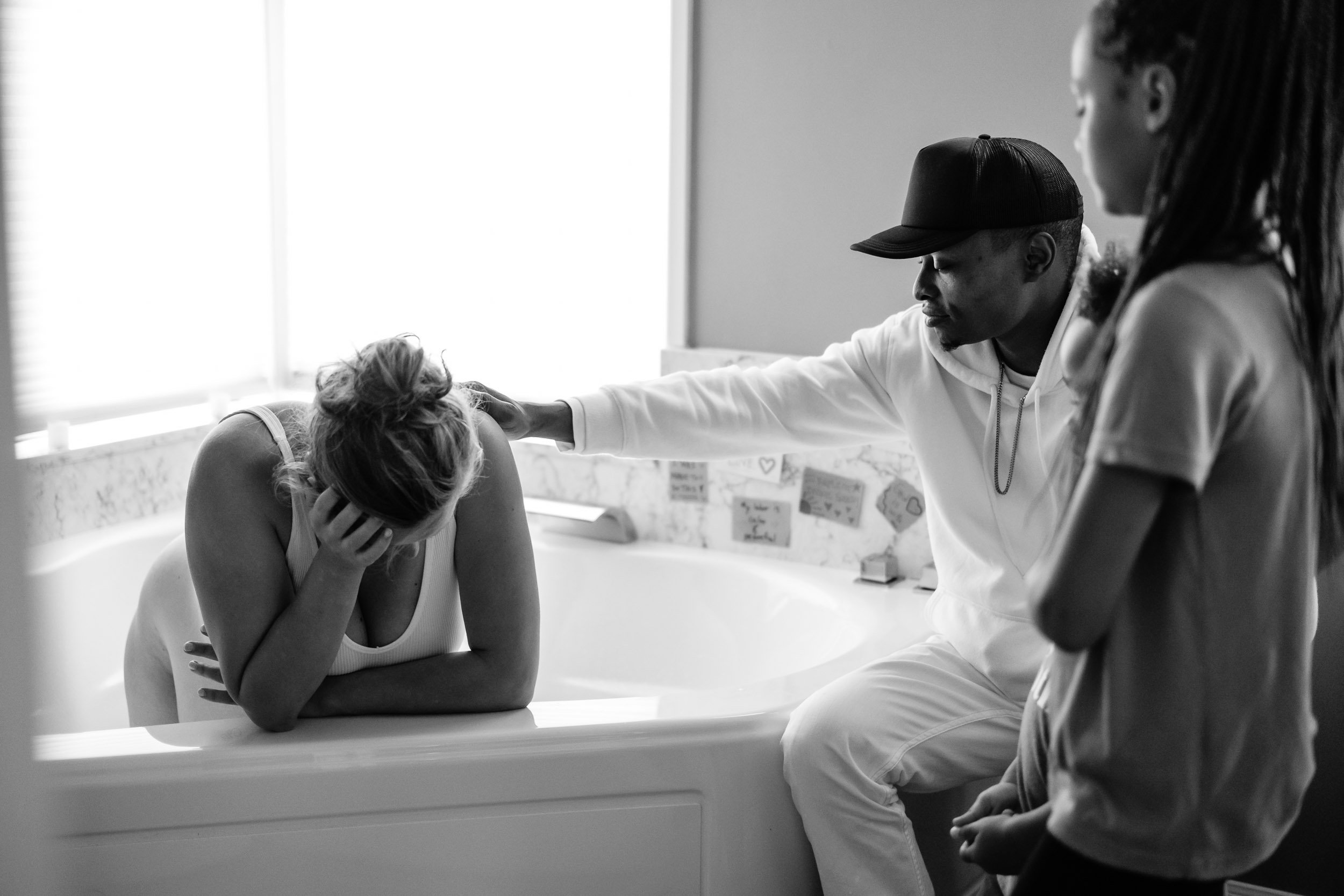 A husband reaches out to support his wife in labor in the birthing tub at Puget Sound Birth Center.