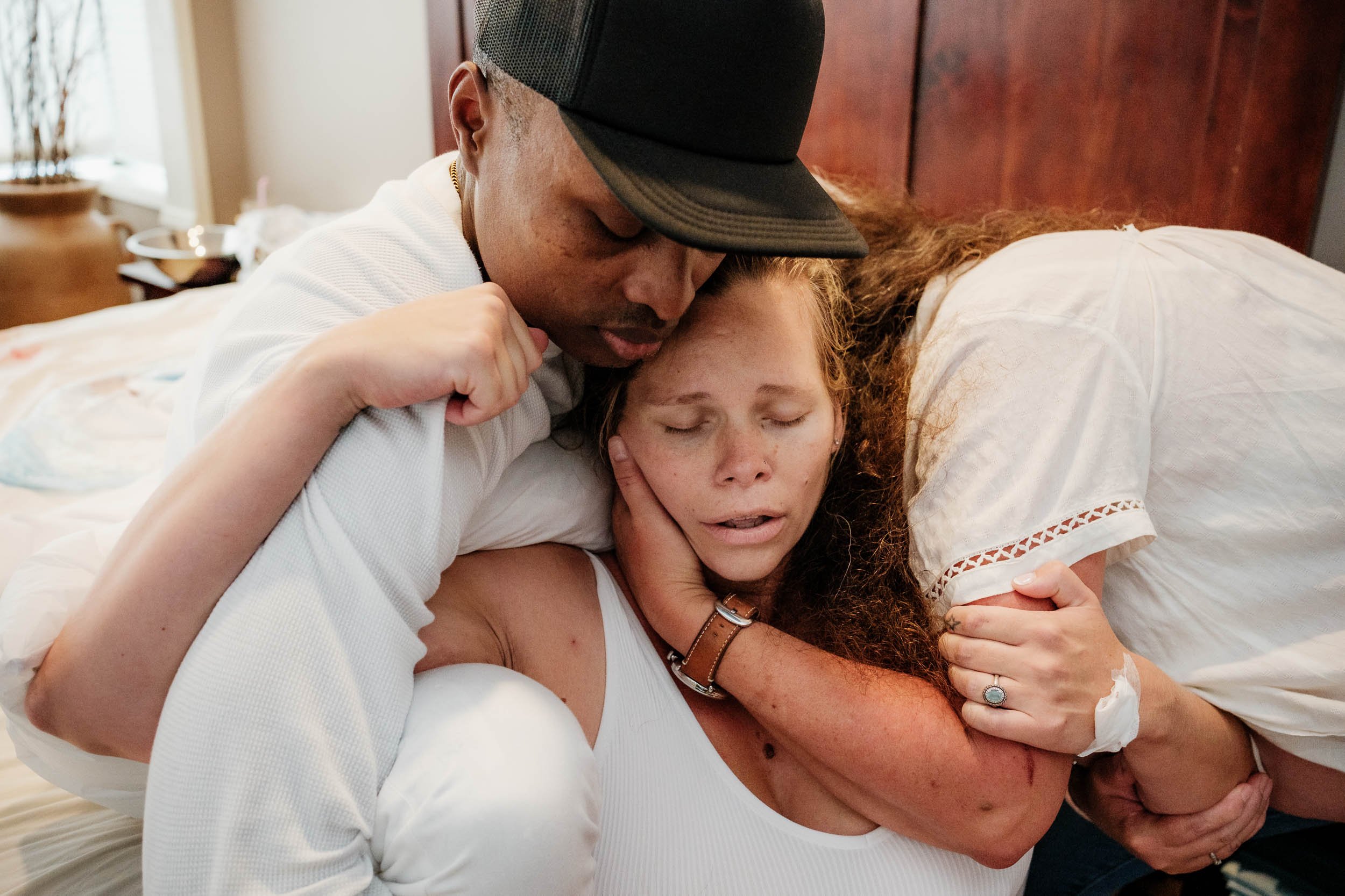 A mother grips her husband and mother between contractions while pushing out her baby at Puget Sound Birth Center.