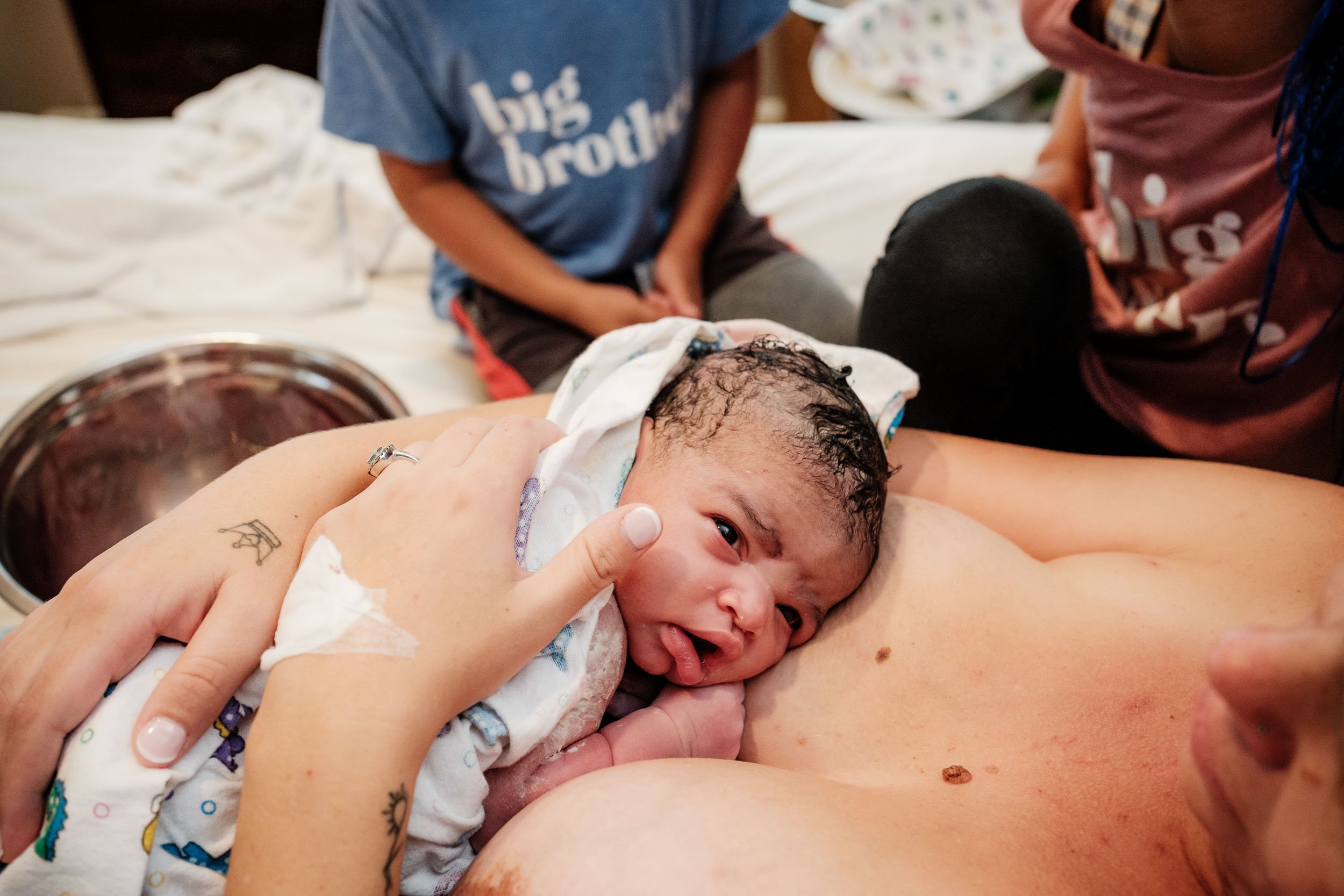 A newborn baby rests on her mother's chest immediately after birth.