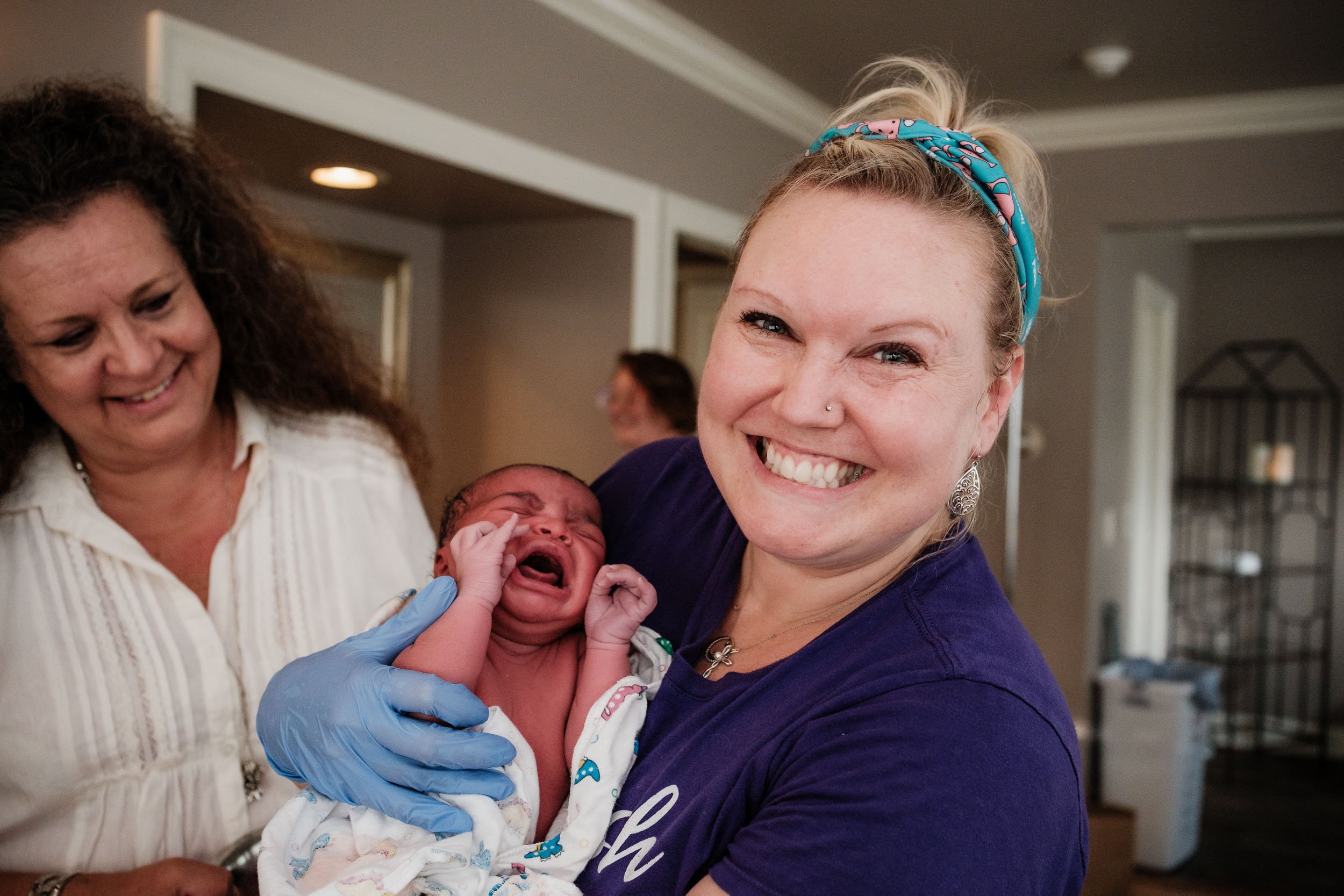 A midwife at Puget Sound Birth Center beams with happiness as she holds a freshly born baby.