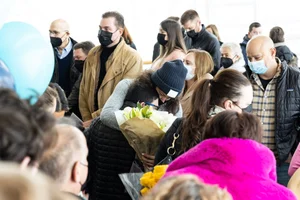  Actor Samuel Floersheimer gets a big hug and. bouquet of lilies in a crowded and colorful lobby 