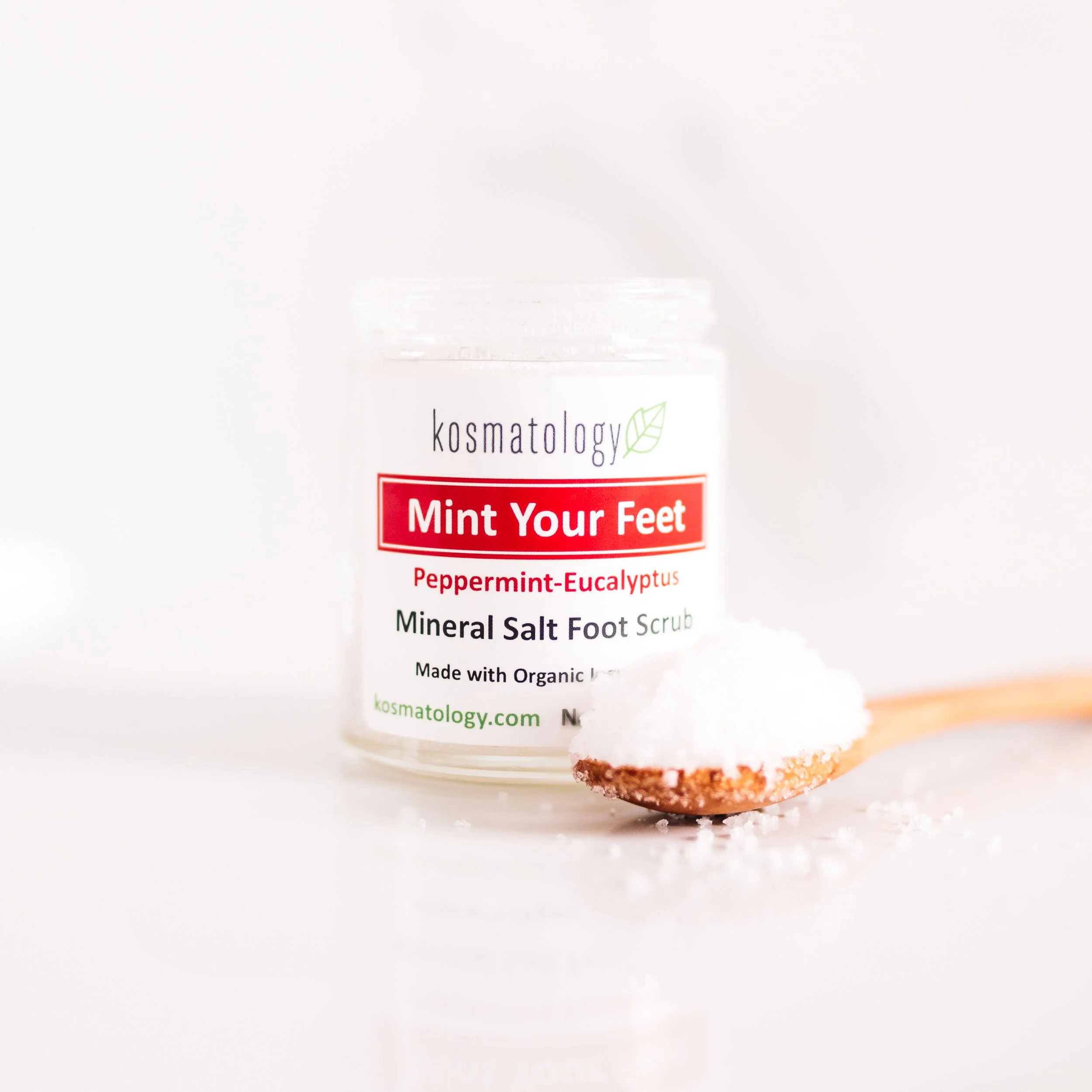 Mint Your Feet Foot Scrub open with a wooden spoonful of scrub in front of the glass jar.