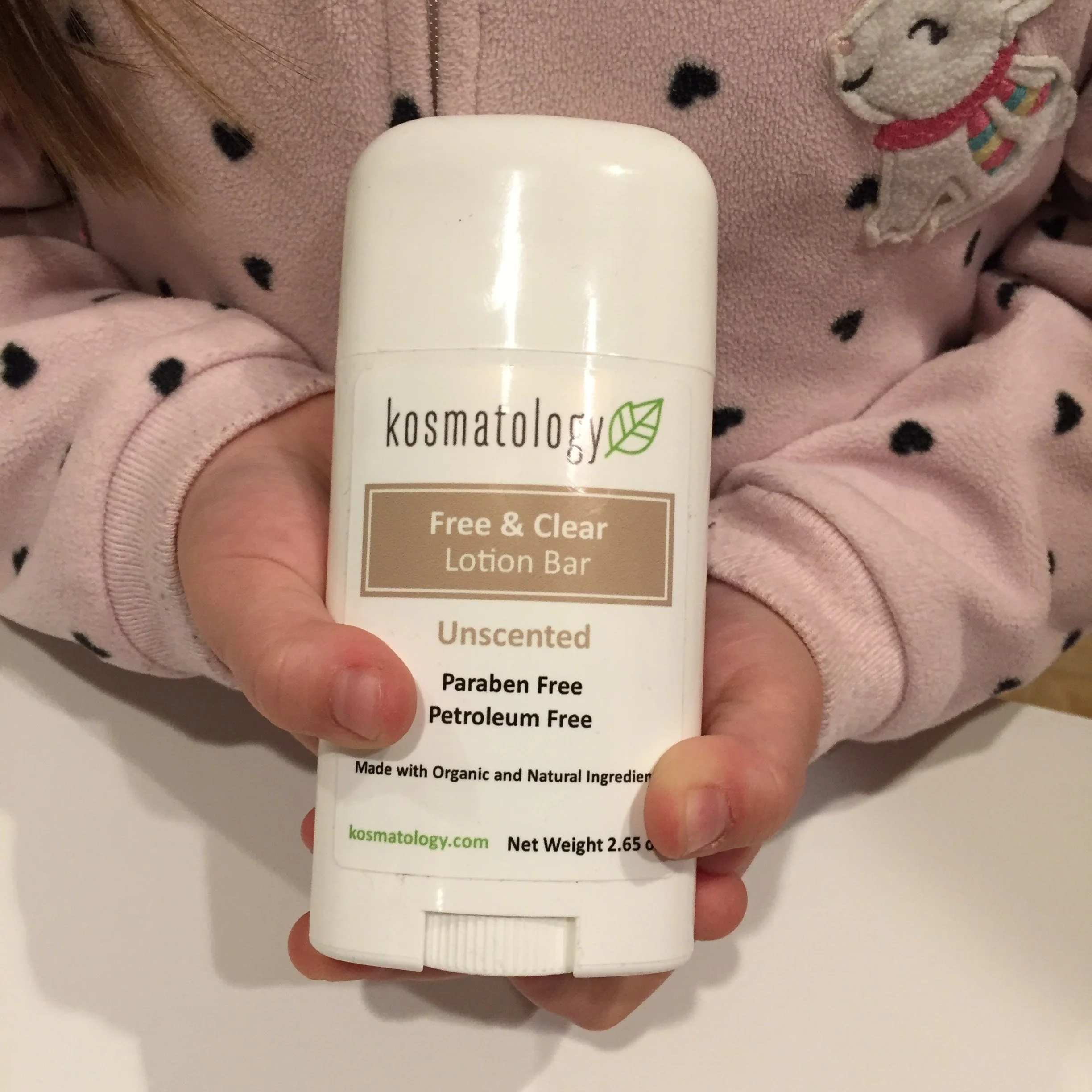 Toddler girl holding a Kosmatology Free & Clear lotion bar