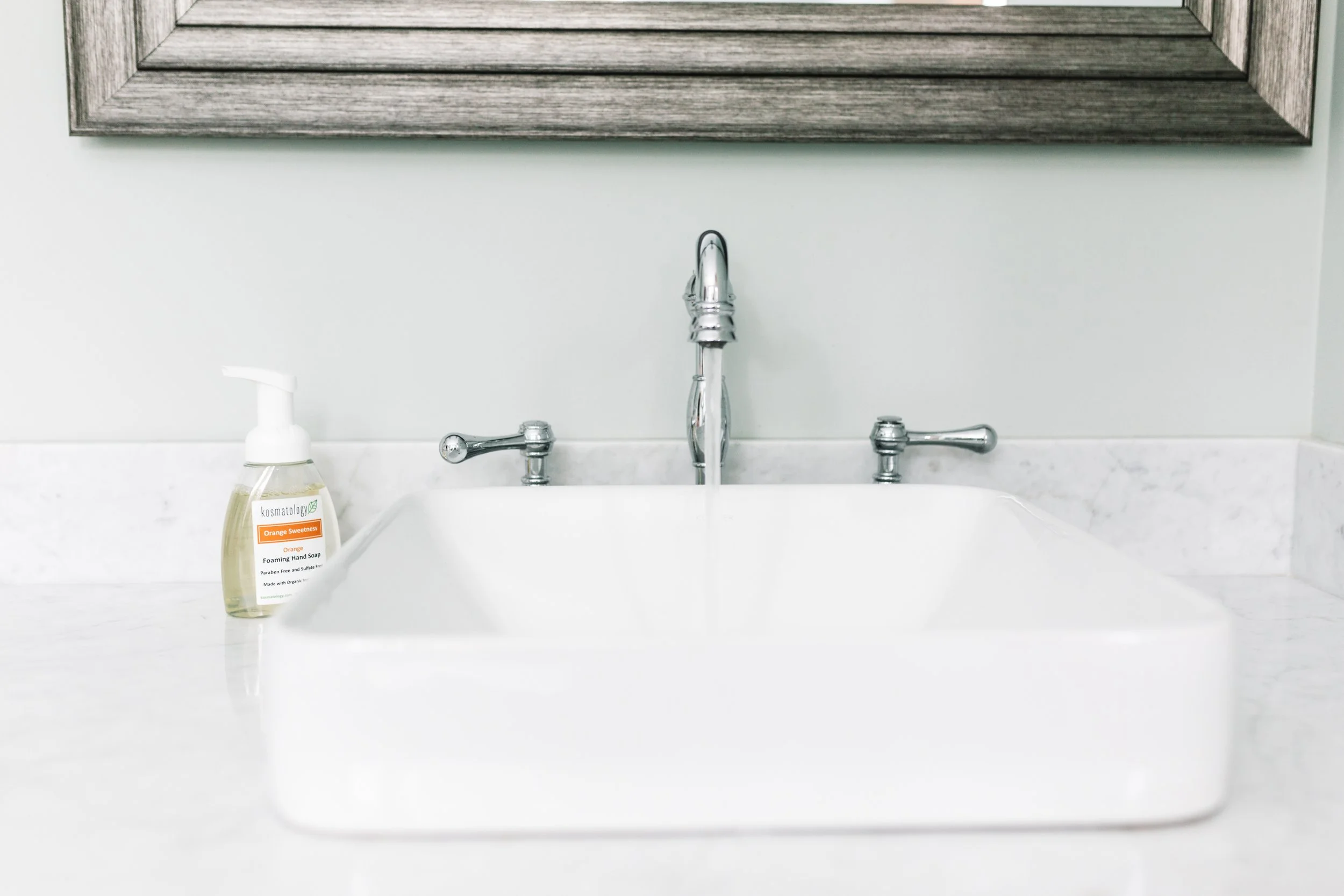Kosmatology Orange Sweetness soap next to a bathroom sink.