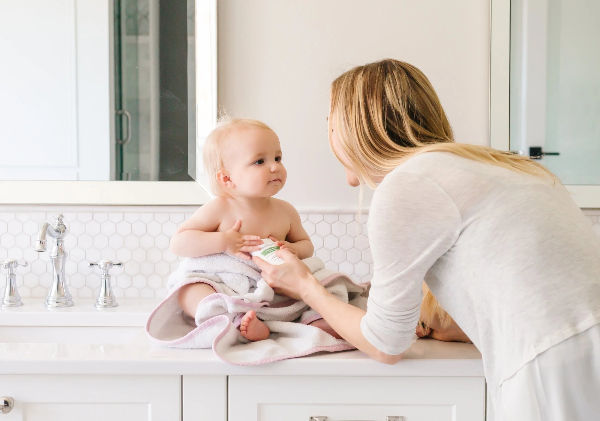 Mom applying Kosmatology lotion bar to baby