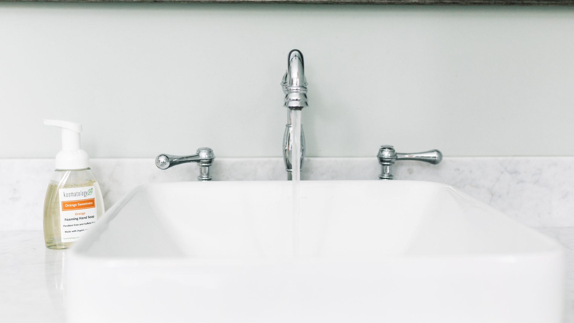 Kosmatology orange hand soap for sensitive skin sitting on a sink counter