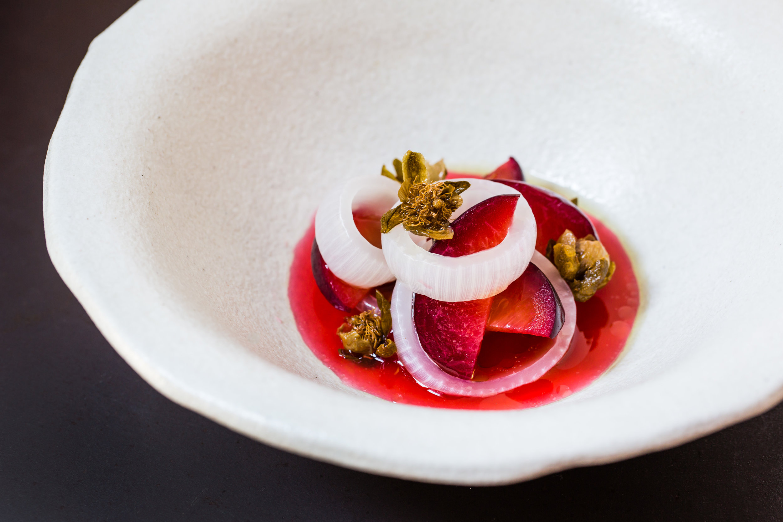 fermented plums, onions and fried capers dish