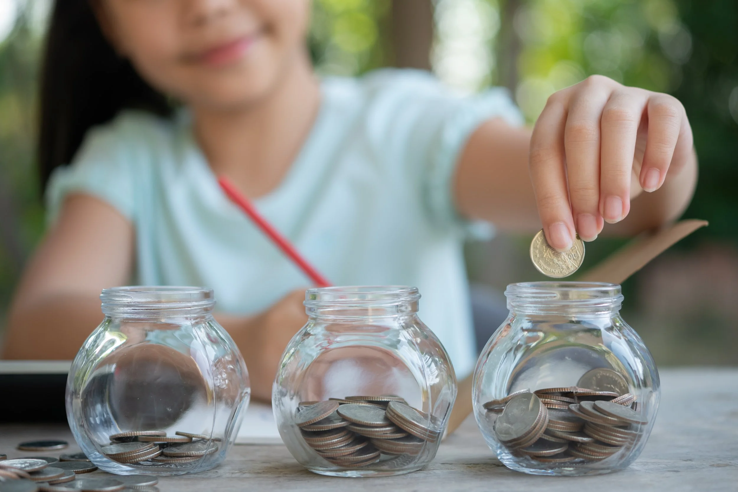 cute-asian-little-girl-playing-with-coins-making-stacks-money-kid-saving-money-into-piggy-bank-into-glass-jar-child-counting-his-saved-coins-children-learning-about-future-concept.jpg