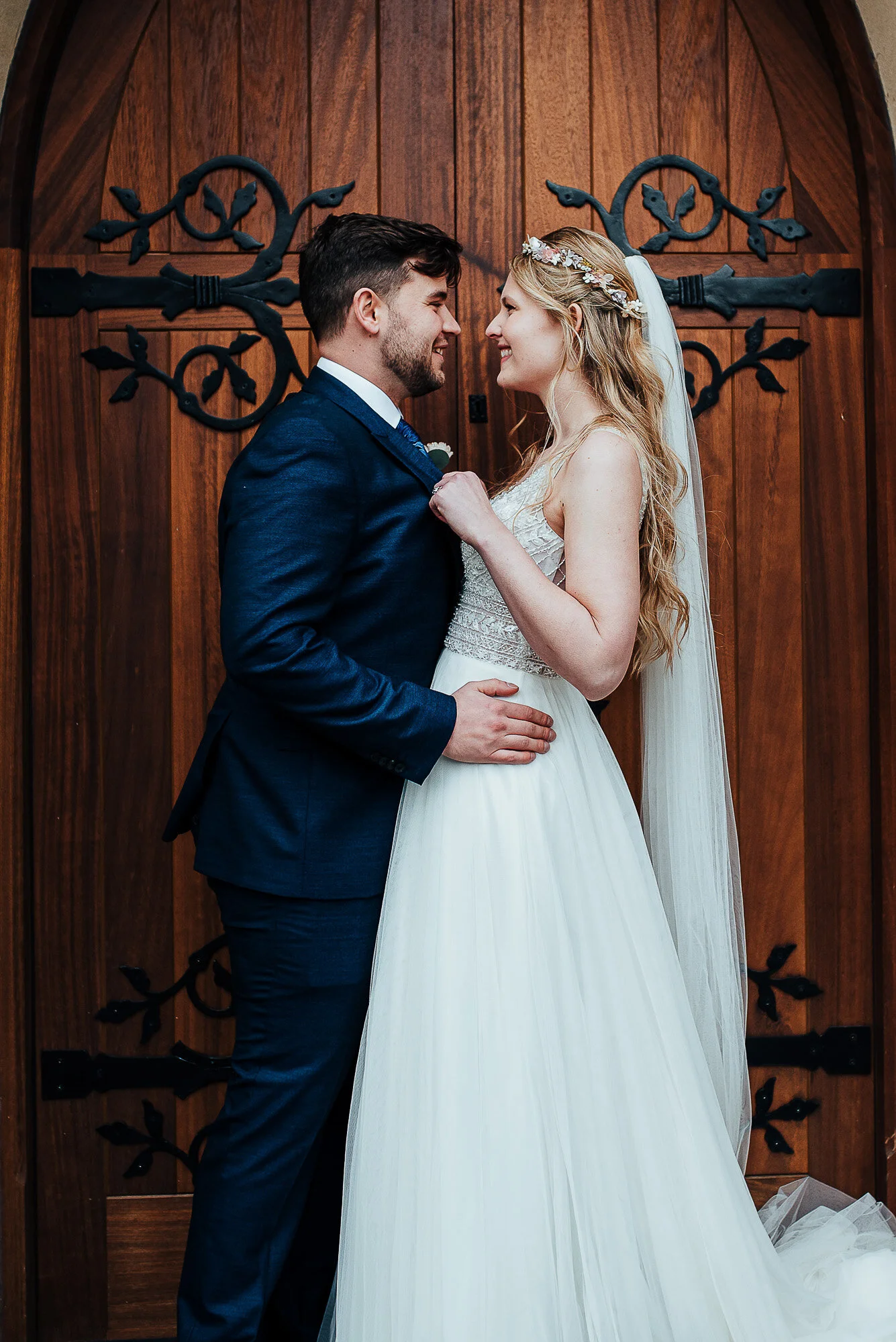 Bride and groom embracing in front of wooden door.