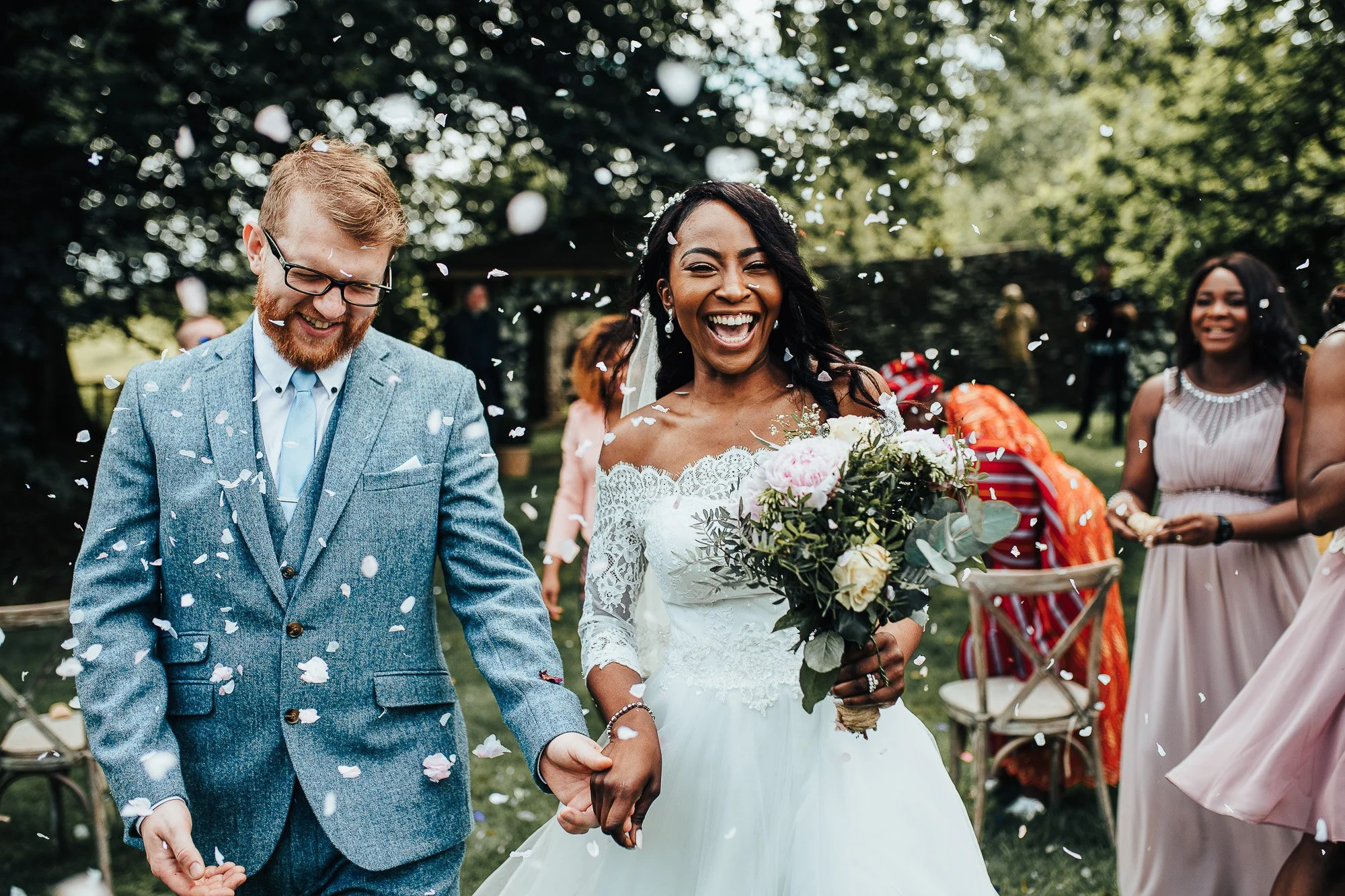 Bride and groom celebrating outdoors with confetti and guests.