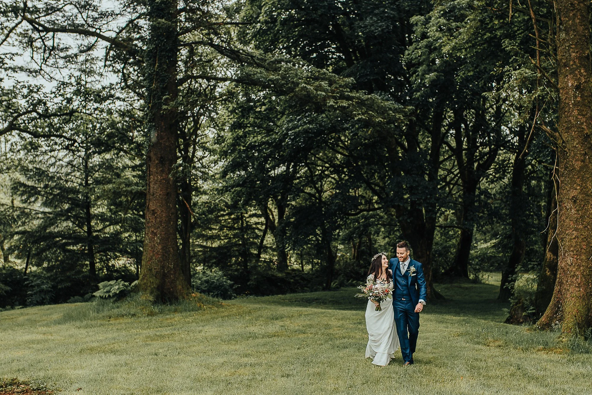 Bride and groom walking in a lush forest setting