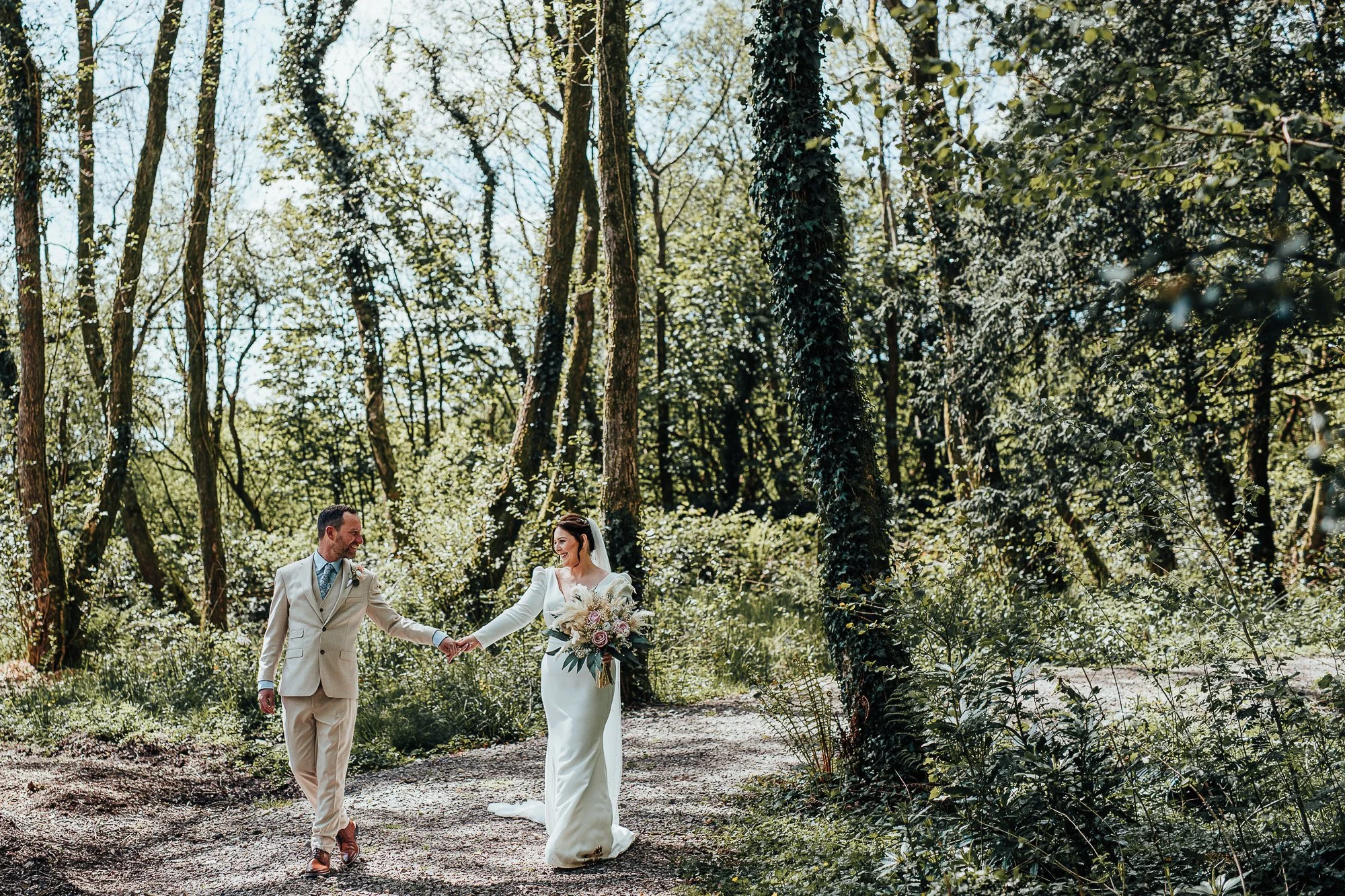 Bride and groom walking hand in hand in a forested area