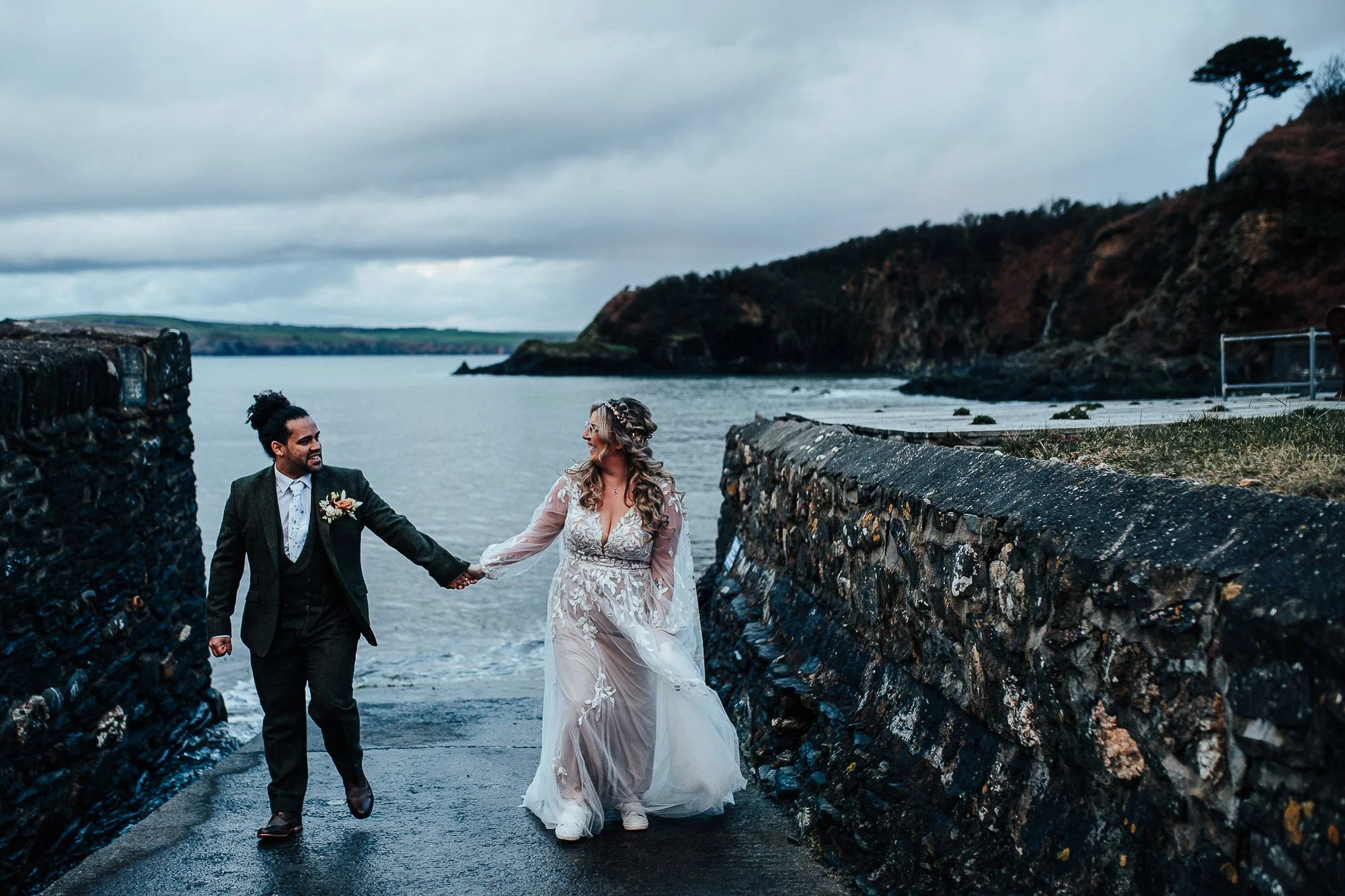Bride and groom walking hand in hand by the sea