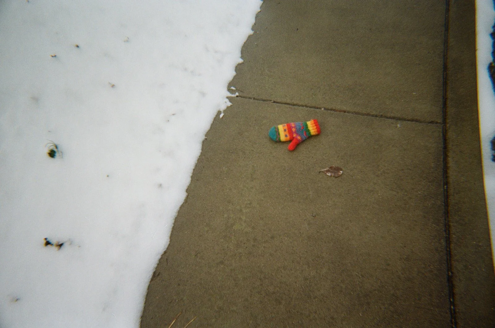Colorful Christmas stocking-shaped sock on a sidewalk next to snow.