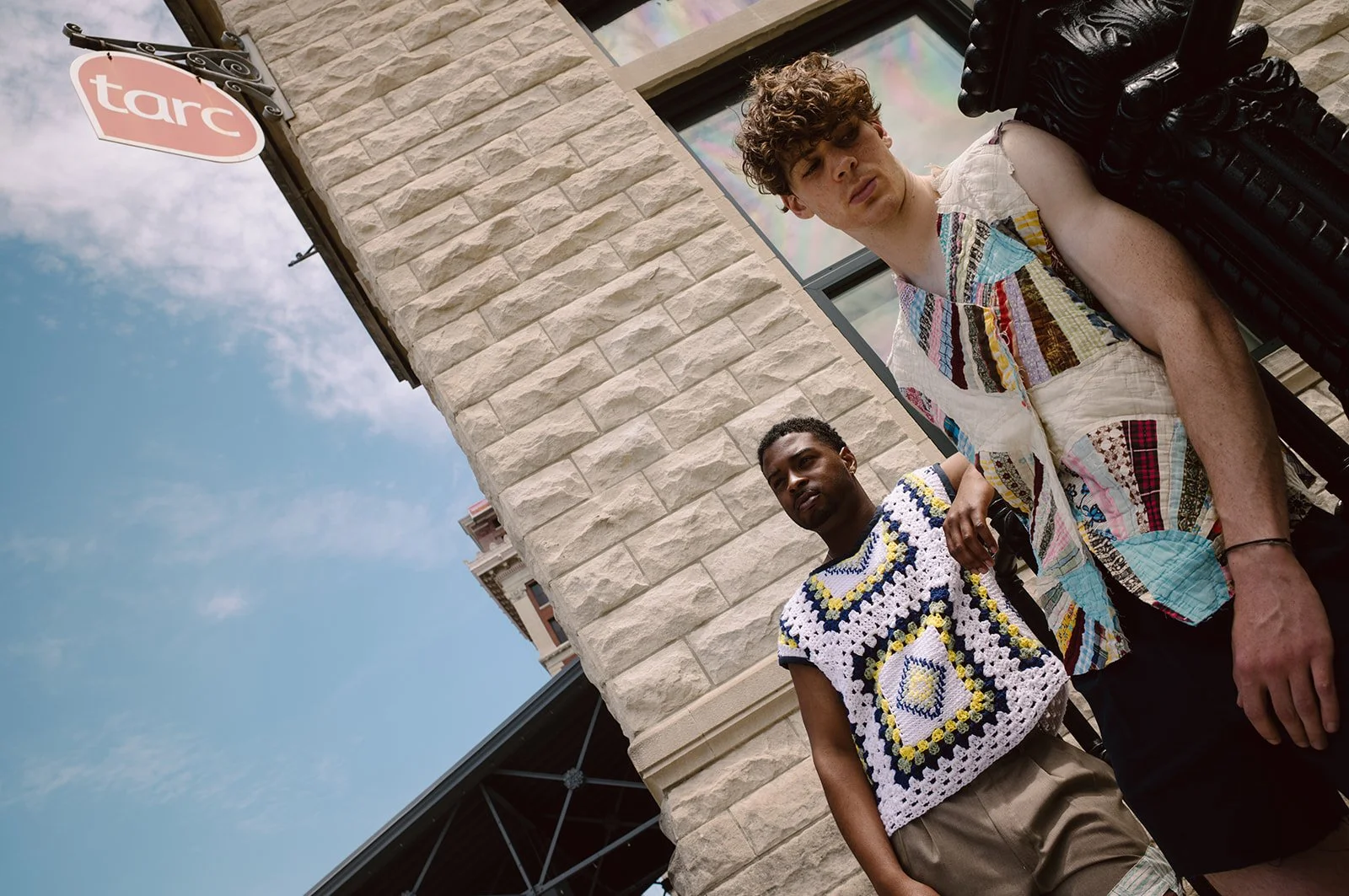 two men in knit outfits stand under a historic building