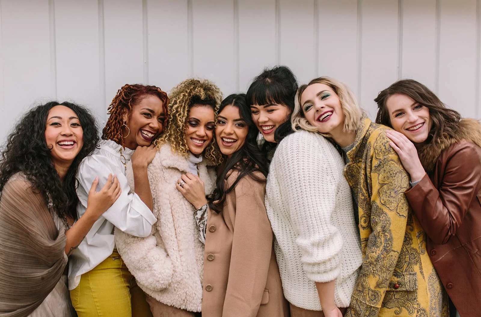 Group of eight women laughing together indoors.