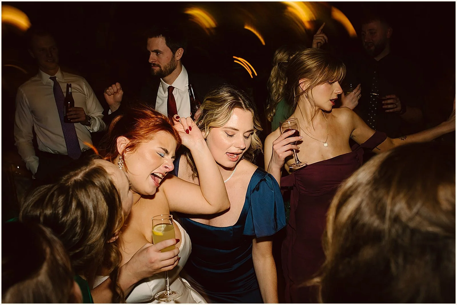 A bride dances with friends on a crowded dance floor.
