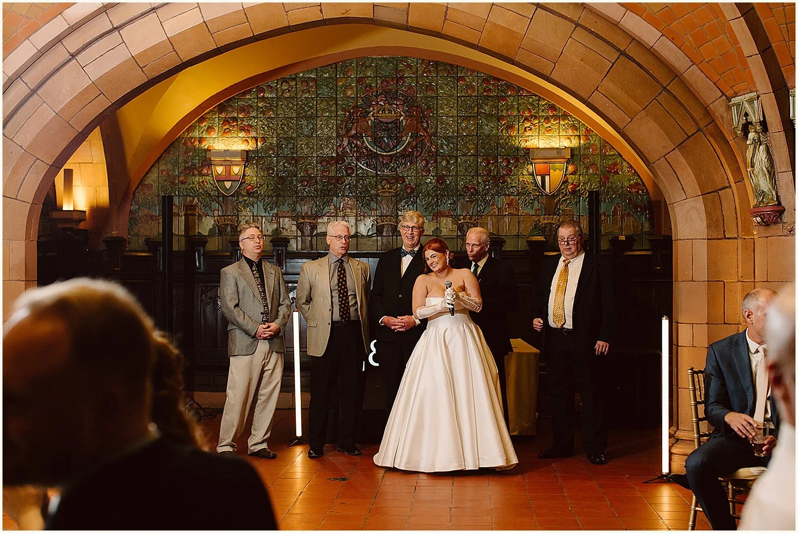 A bride laughs as she speaks into a microphone at a Seelbach Hotel wedding.
