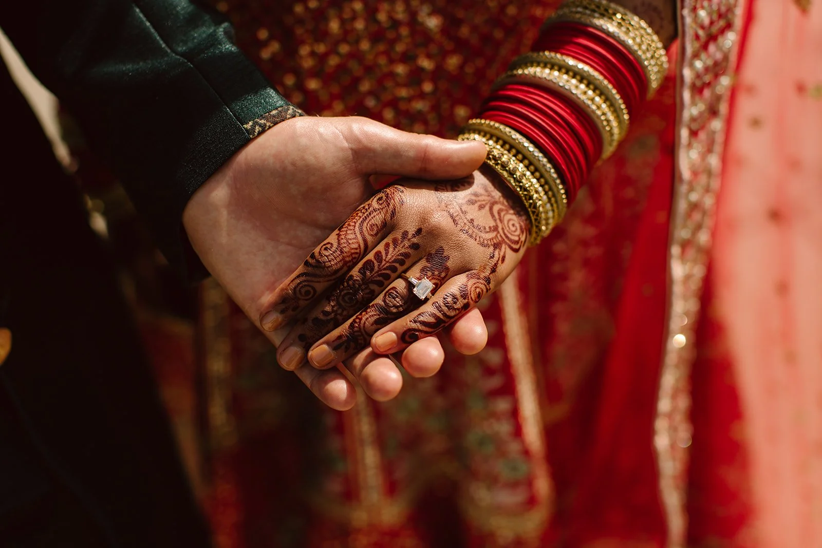couple holds hands together at wedding, bride has henna on hers