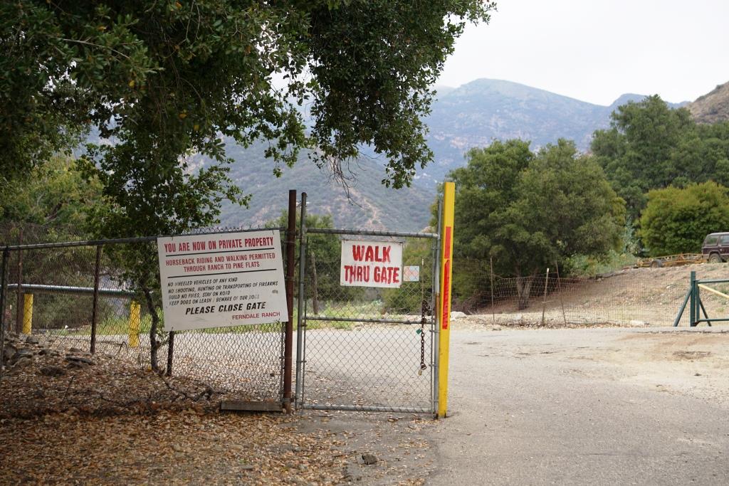You will be veering left after walking through this gate, into private property. You will be walking past an oil pump then into an avocado orchard, then past another oil rig (veer left) to the trailhead.