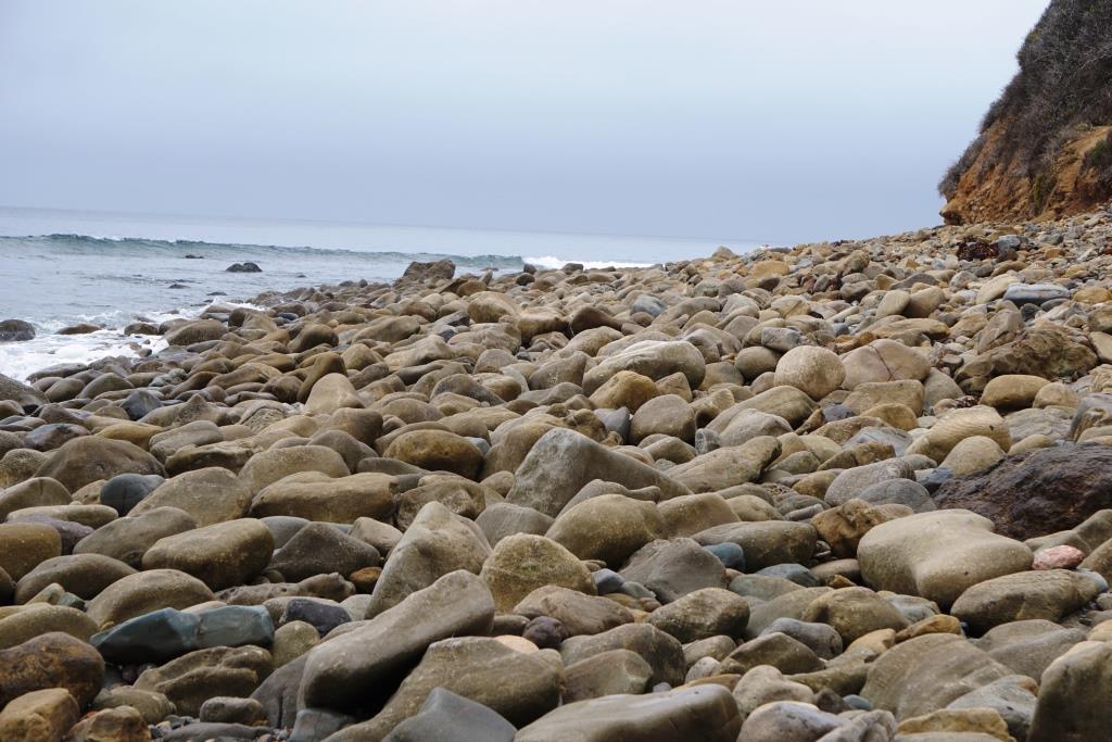 Rocks about on the west side of the beach, which stretches around to residences.