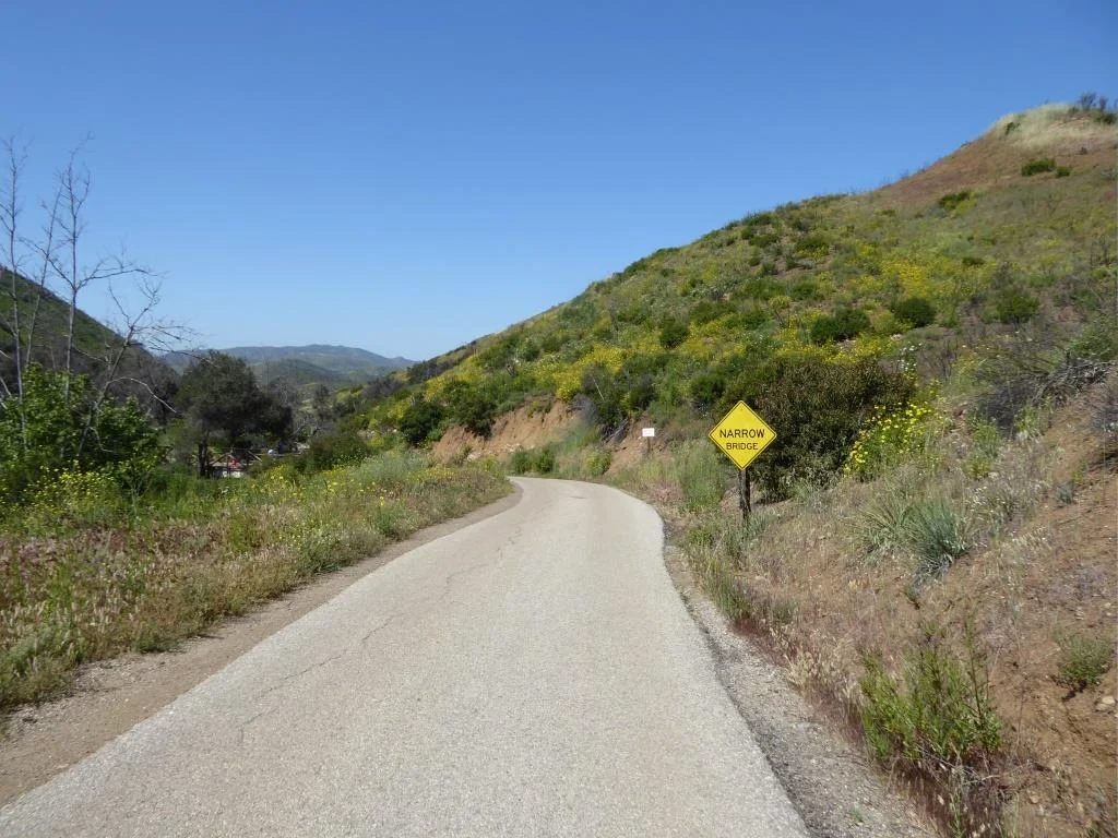 The "Narrow Bridge" sign marks the bottom of the steep initial grade down Sycamore Canyon Fire Road. You'll cross the bridge, then see the Upper Sycamore Canyon Trail entry to the left.