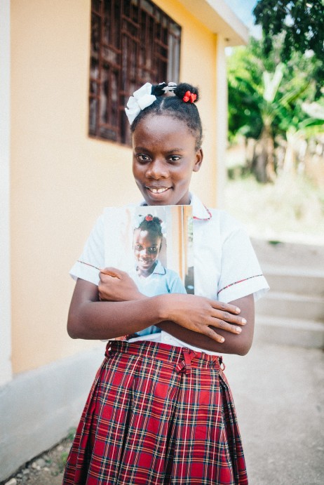 Nellie holds her portrait, and was the winner of the changemaker competition for her short documentary on building a road in her community.