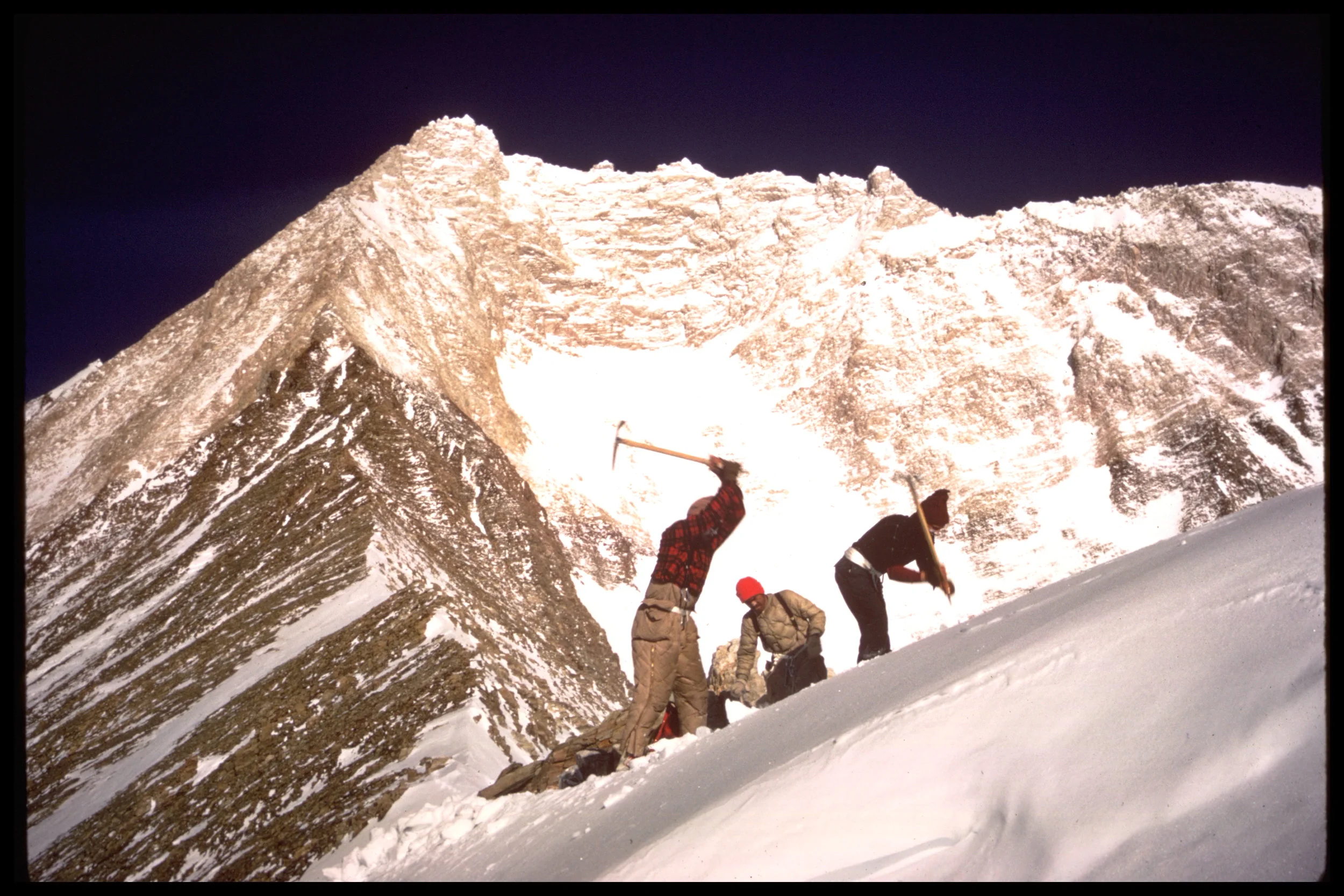 These mountaineers are cutting a tent platform with their ice axes