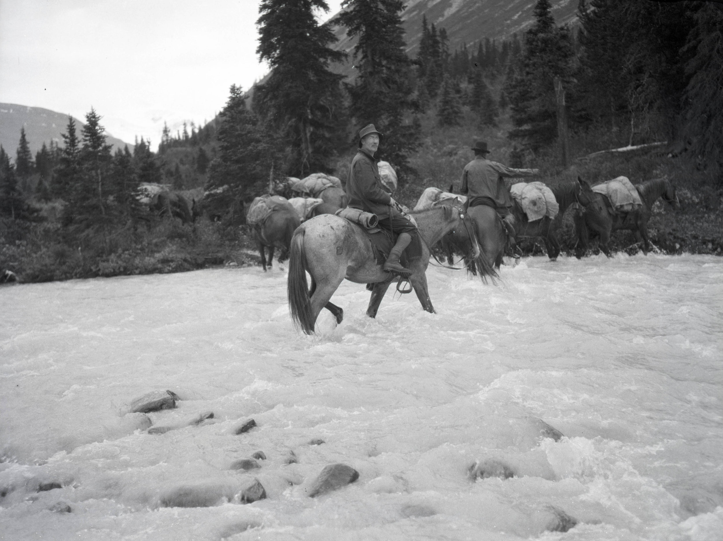  The climbing party fording a river on horses, there were fewer roads and cars were less reliable, so travel by horse was common 