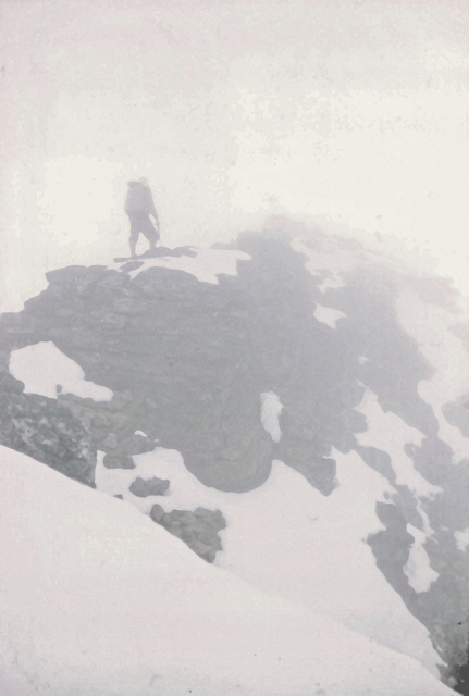  Below Balcony Camp, we found the rocks deeply buried, by not unduly difficult. Visibility was about seventy feet. Once past the sharp snow ridge, we started looking for the ice axe marking our cache. 